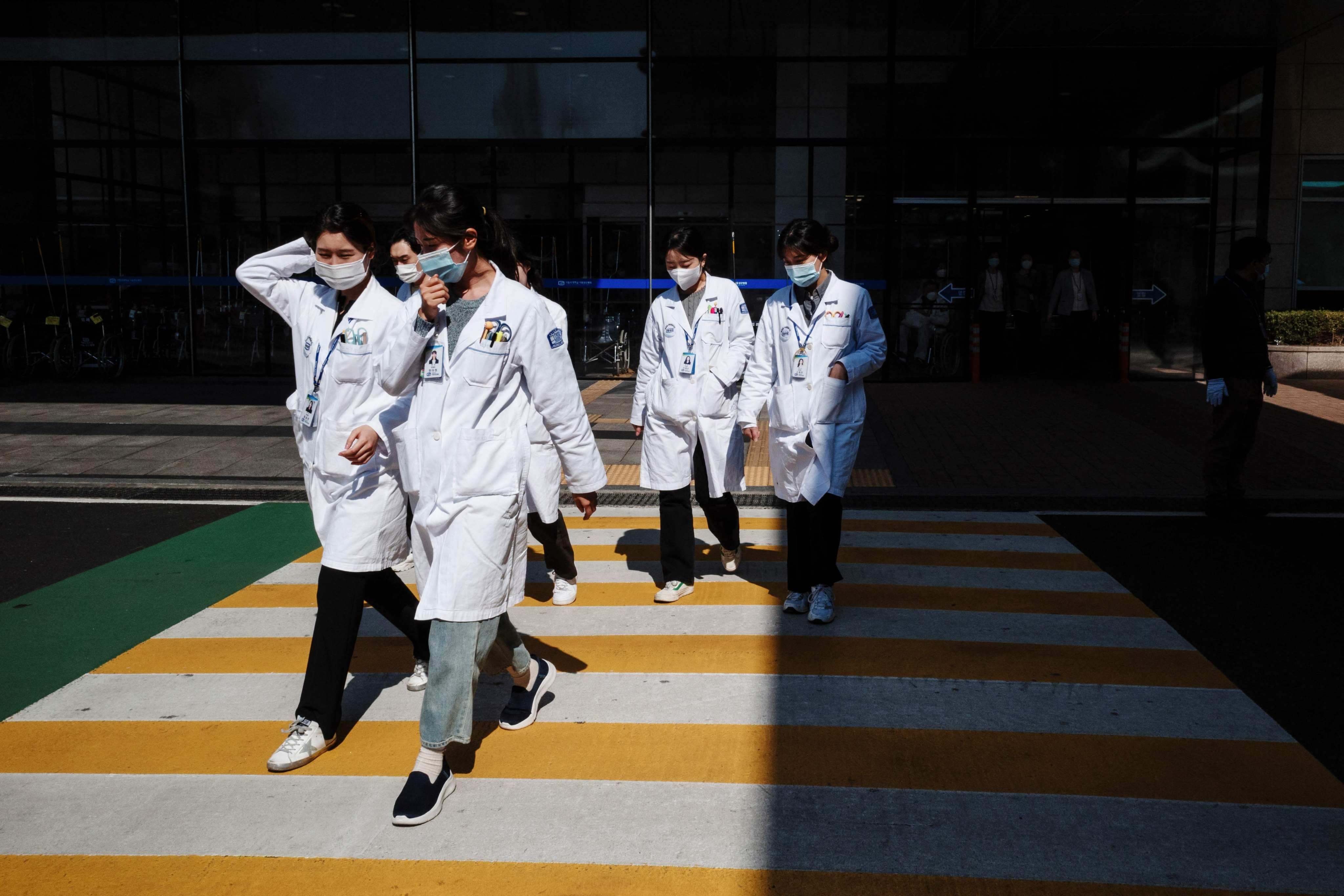 Medical workers walk crossing a street outside a hospital in Seoul. The South Korean government said it will adjust medical school quotas in a bid to end a walkout by junior doctors. Photo: AFP