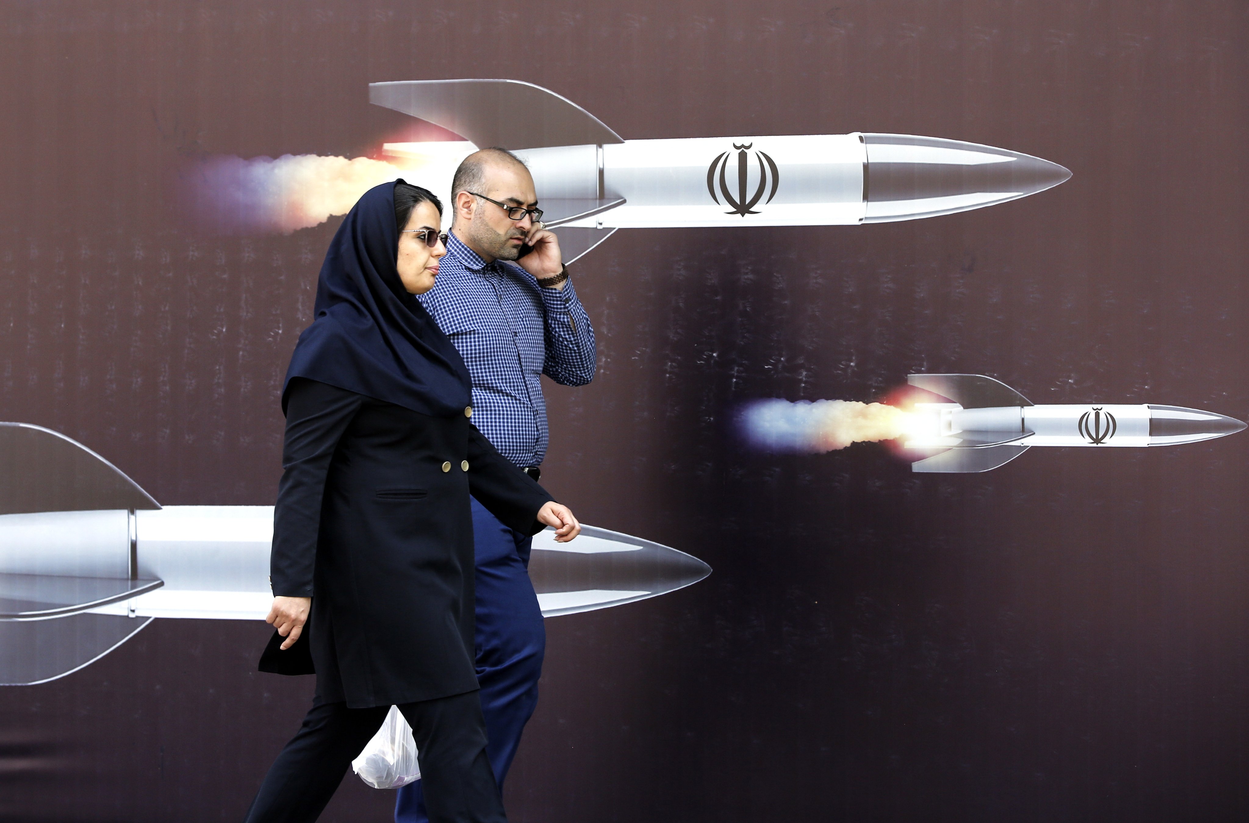 epa11287873 Iranian people walk past a huge anti-Israeli banner carrying pictures of missiles, in Tehran on Thursday. Photo:  EPA-EFE