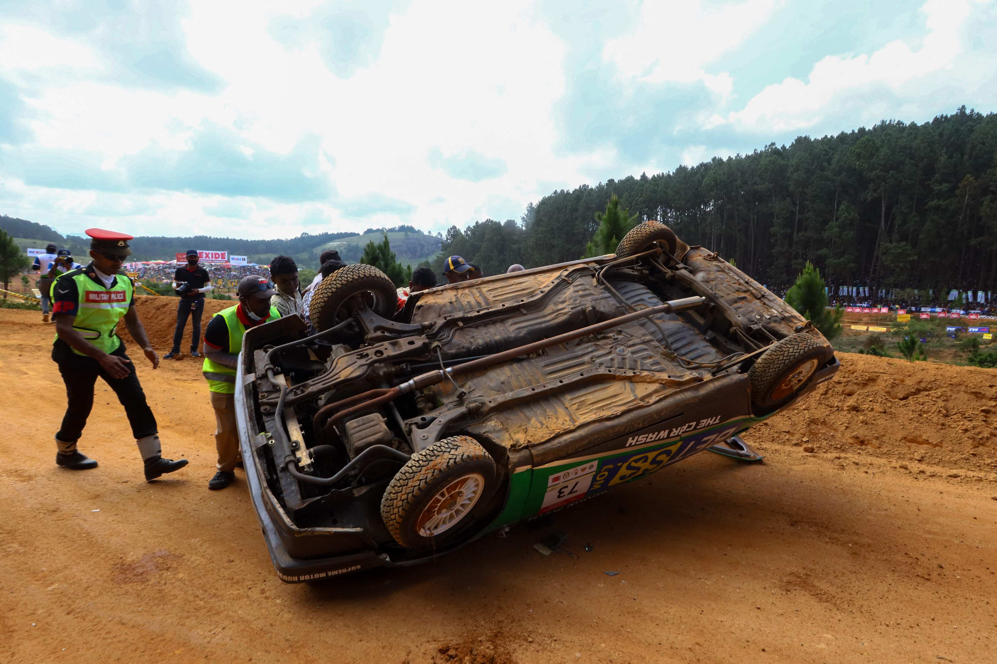 Track attendants inspect a car that came off a racetrack in Diyatalawa, Sri Lanka, on Sunday. Thousands of spectators looked on as the mishap took place. Photo: AFP