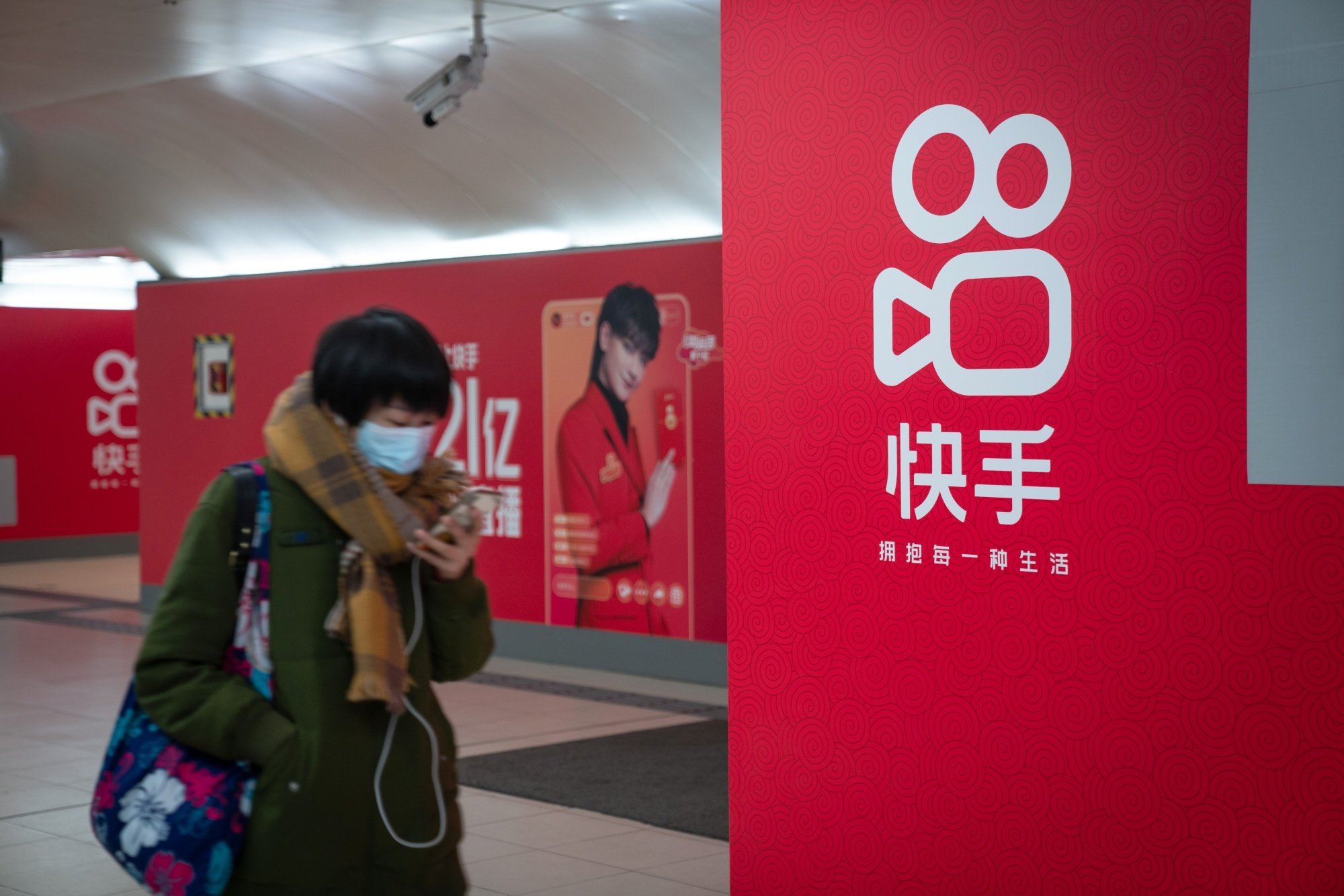 A passenger walks past a Kuaishou ad in a subway station in Beijing, February 3, 2021. Photo: Bloomberg