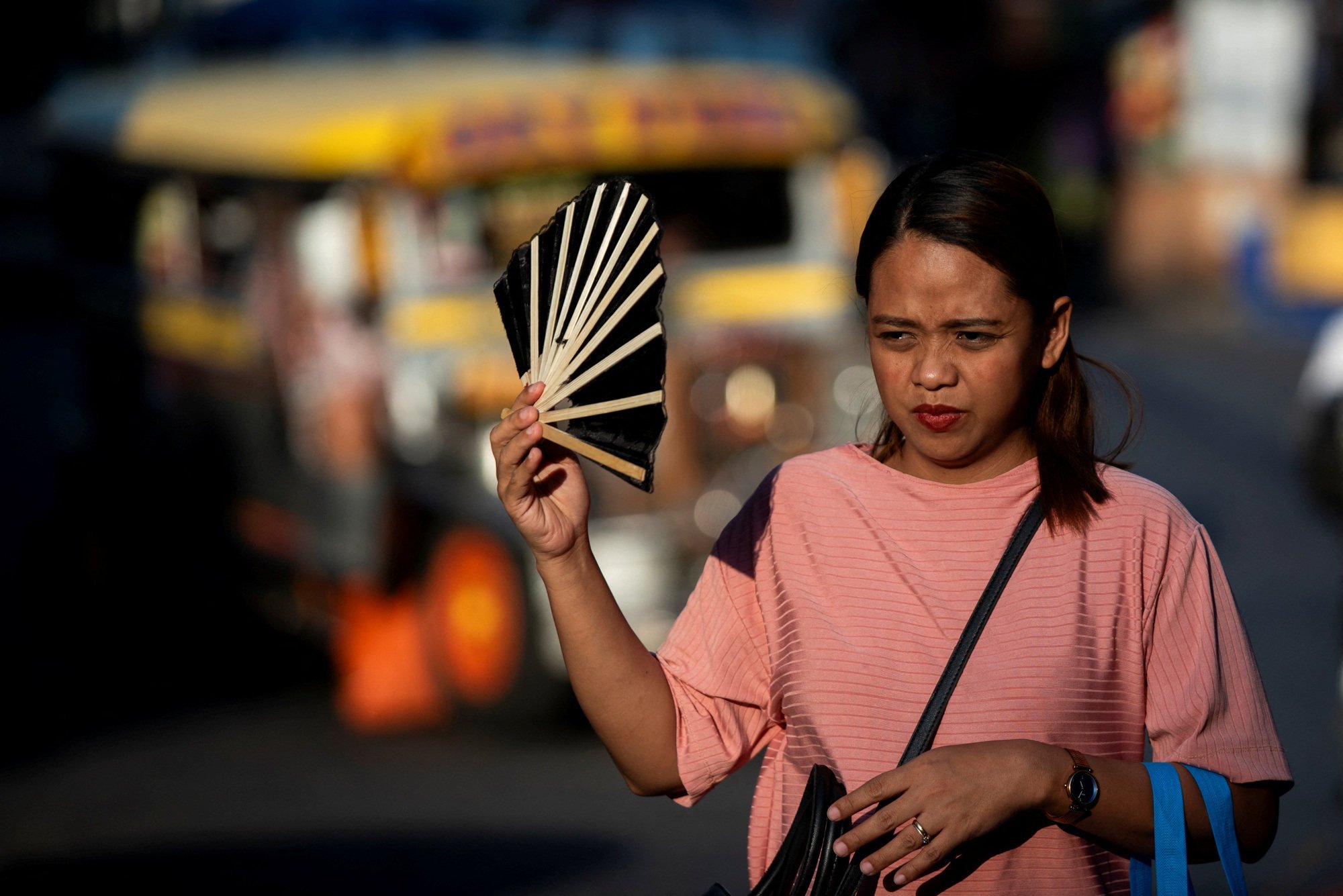 A woman uses a hand fan to cool herself down during a hot day in Manila last week. Sweltering temperatures in the Philippine capital have forced many schools to switch to remote learning. Photo: Reuters