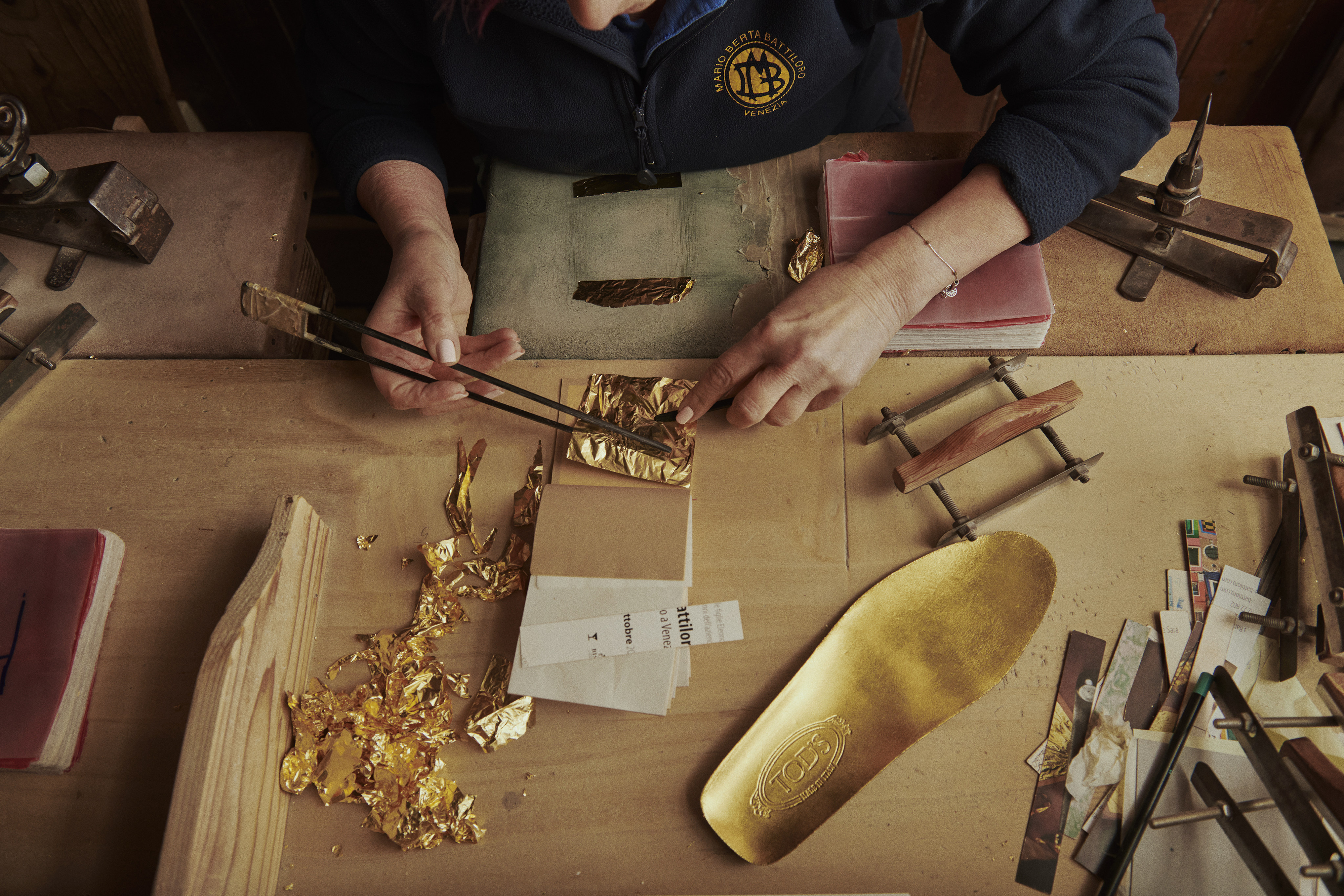 Goldbeating artisans Marino Menegazzo and Mario Berta Battiloro gilding a pair of Gomminos with gold leaf. Photo: Tod’s