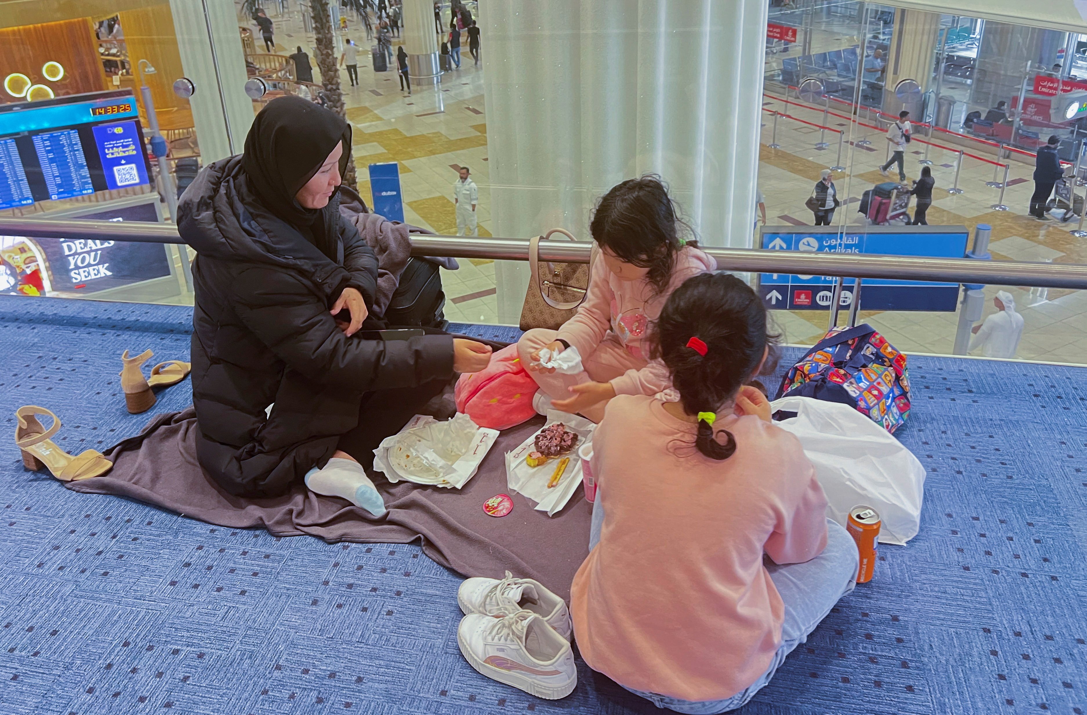 A woman and her daughters eat as they wait for their flight after a rainstorm hit Dubai, causing delays at Dubai International Airport, United Arab Emirates. Photo: Reuters