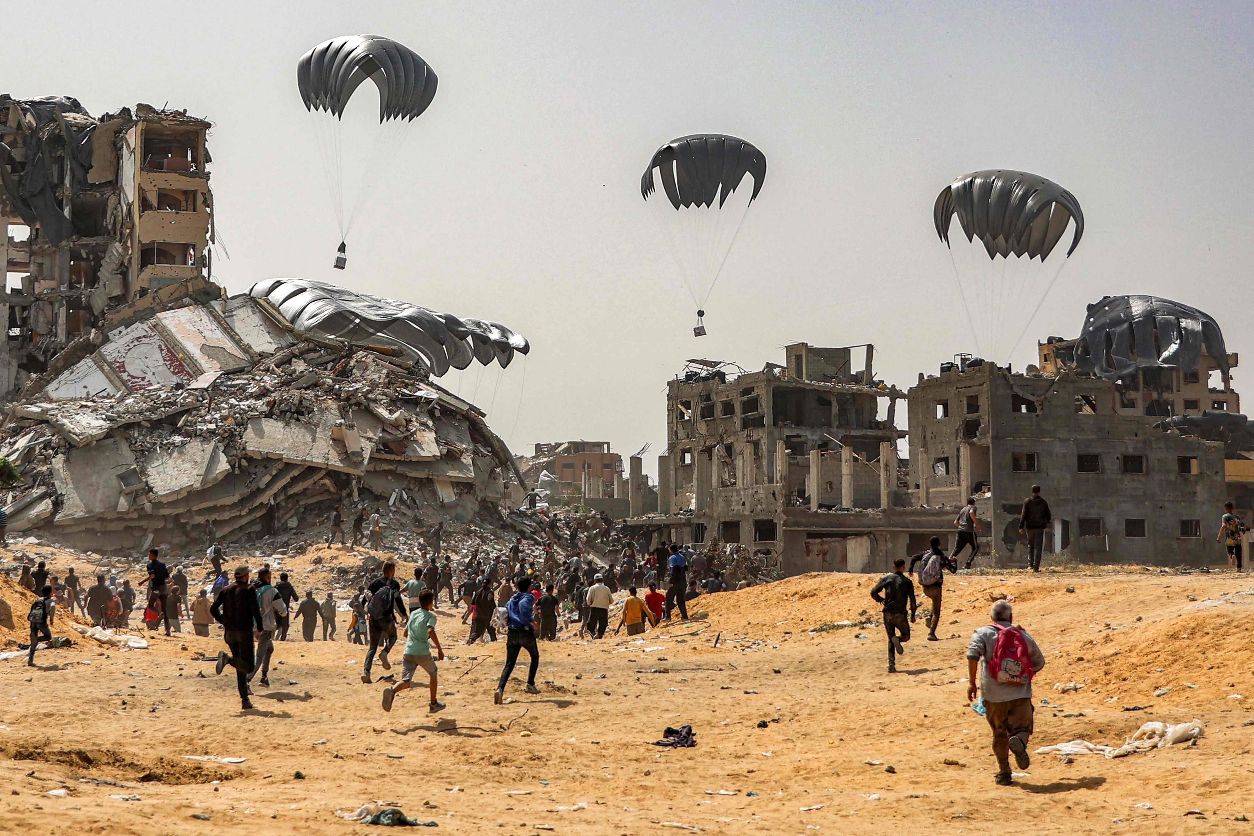 People rush to landing humanitarian aid packages dropped over the northern Gaza Strip on April 23, 2024 amid the ongoing conflict in the Palestinian territory between Israel and the militant group Hamas. Photo: AFP