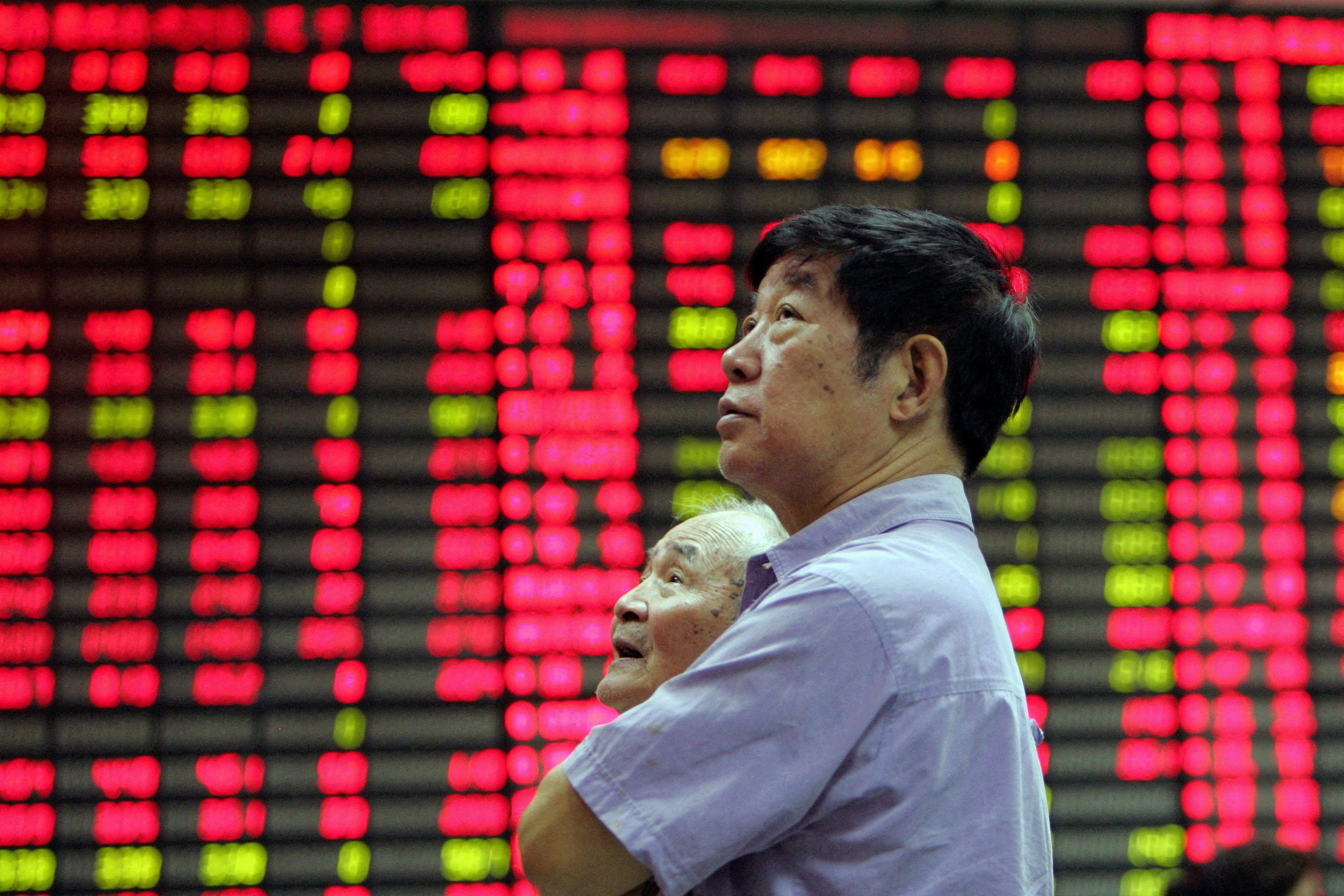 A man stands in front of an electronic stock board in the stock market of Shanghai. Photo: Reuters