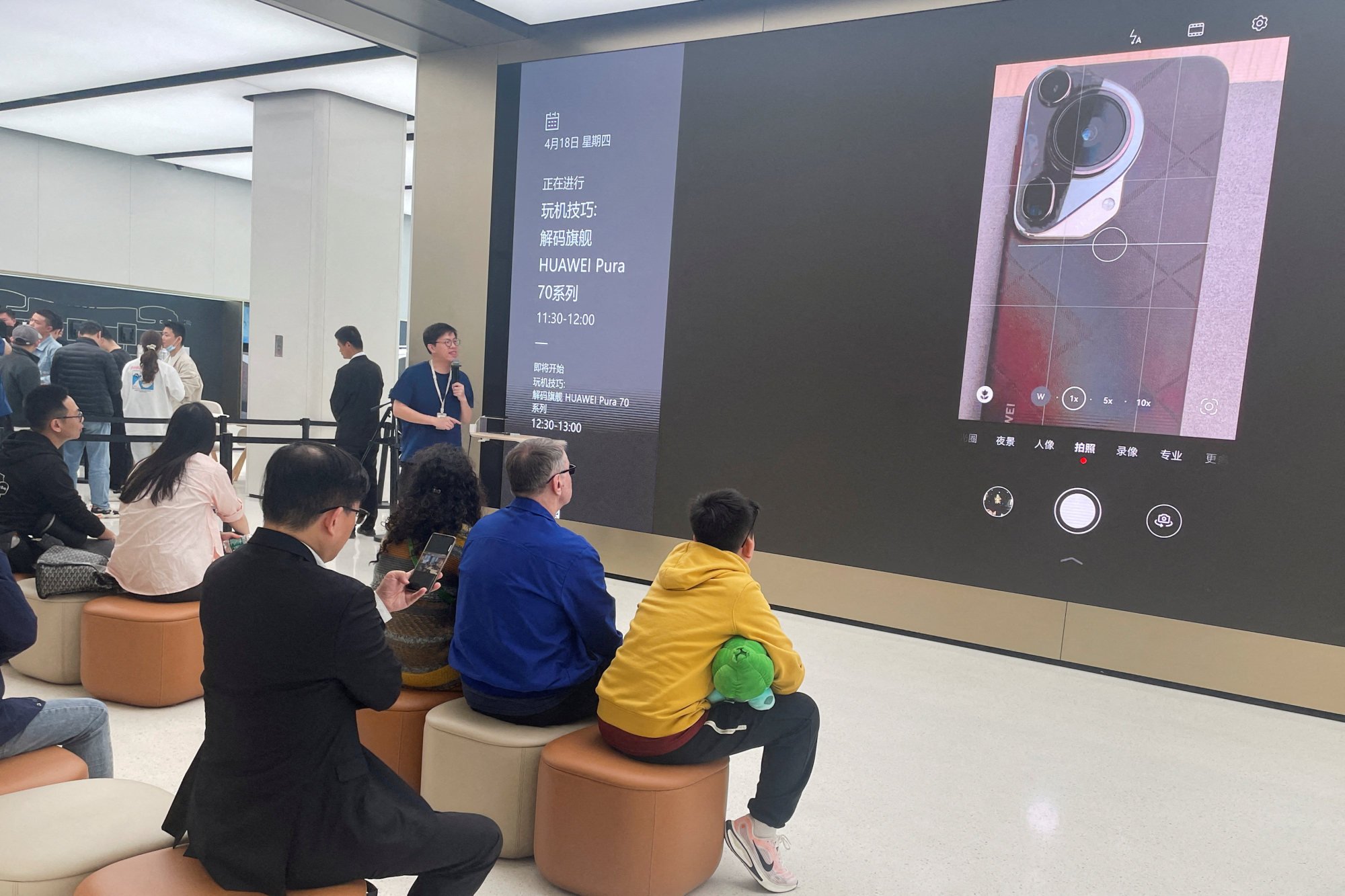 Customers listen to staff introducing Huawei’s new smartphones at the brand’s flagship store in Shanghai, China. Photo: Reuters