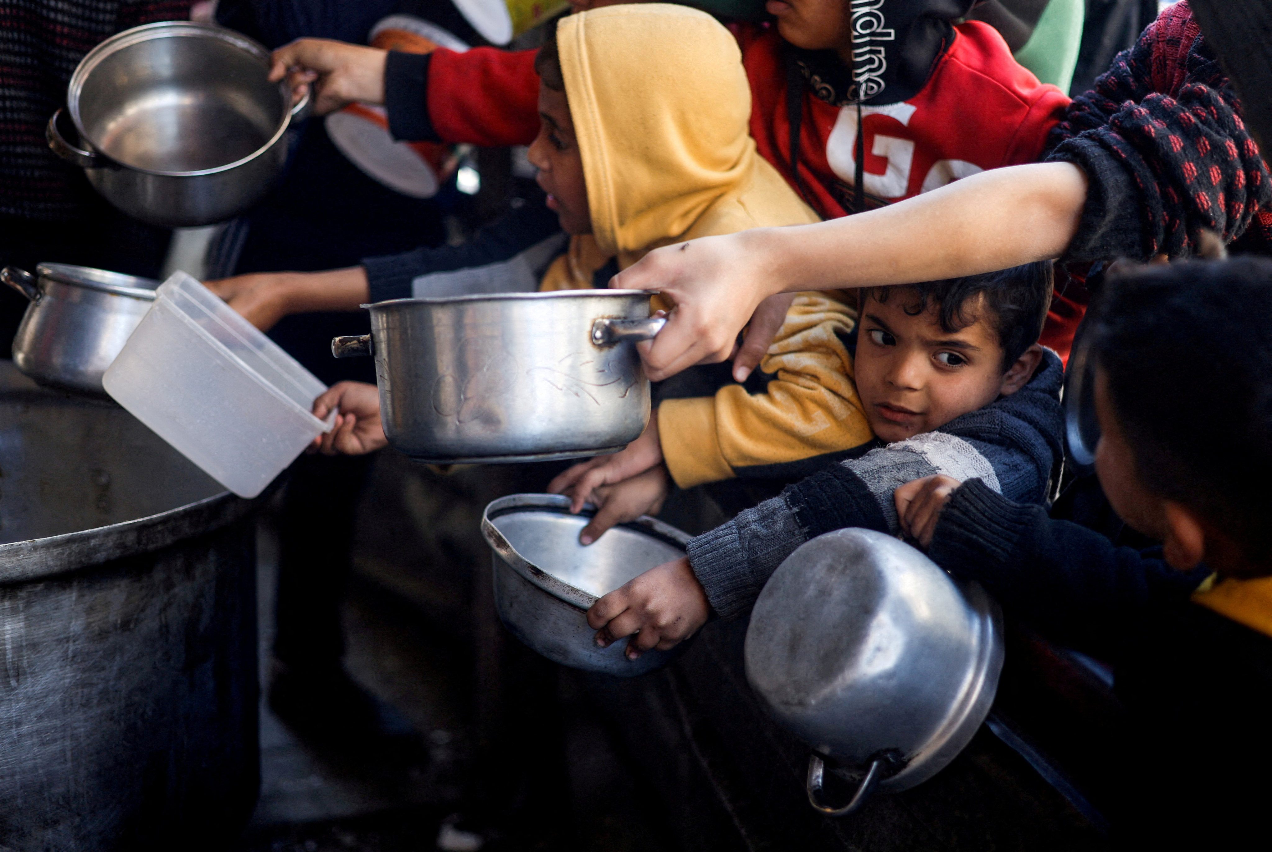 Palestinian children wait to receive food cooked by a charity kitchen in Rafah in March. Photo: Reuters