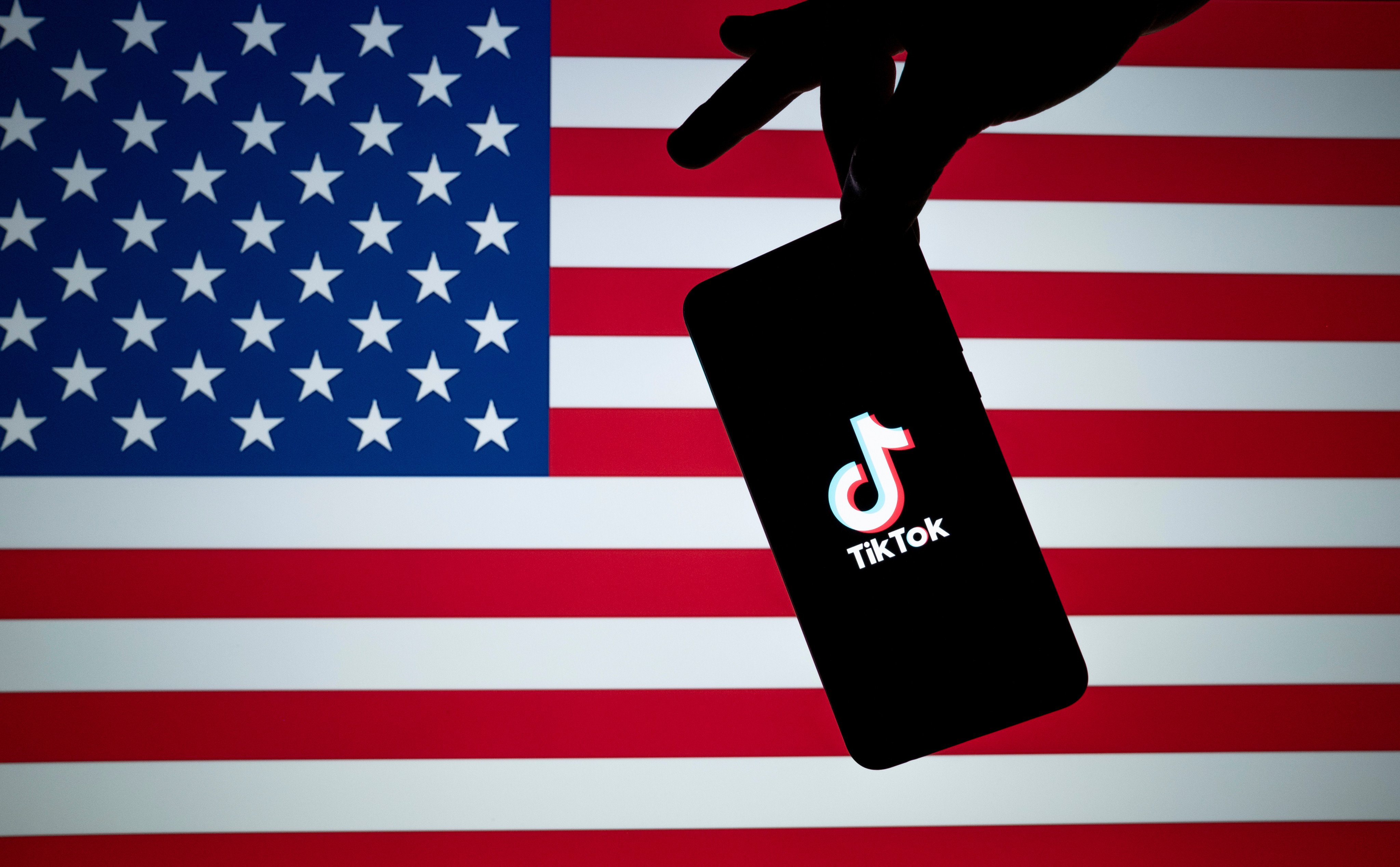 The TikTok logo is seen on the silhouette of a smartphone against an American flag. Photo: Shutterstock