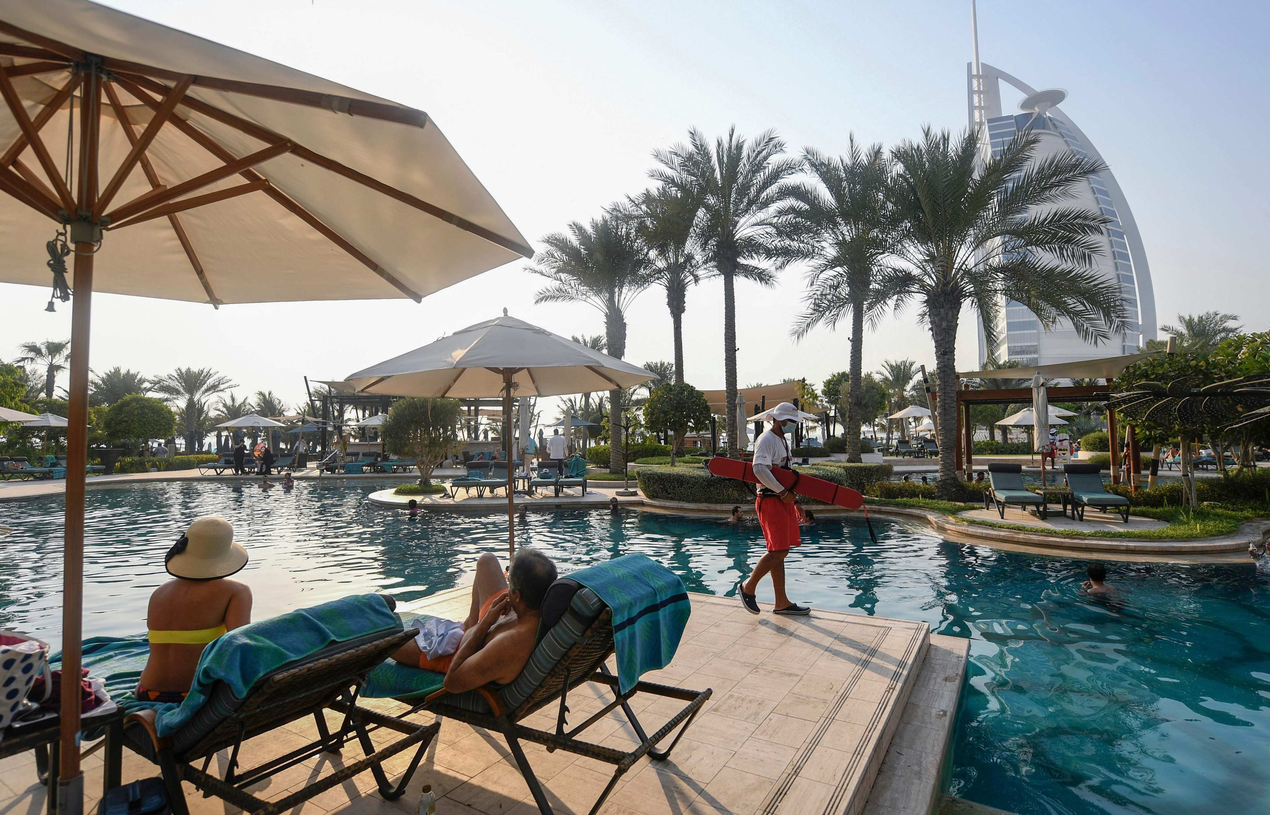 Tourists sunbathe by the pool of the Al Naseem hotel in the Gulf emirate of Dubai in the United Arab Emirates, on July 7, 2020, with a view of the Burj al-Arab hotel in the background. Photo: AFP