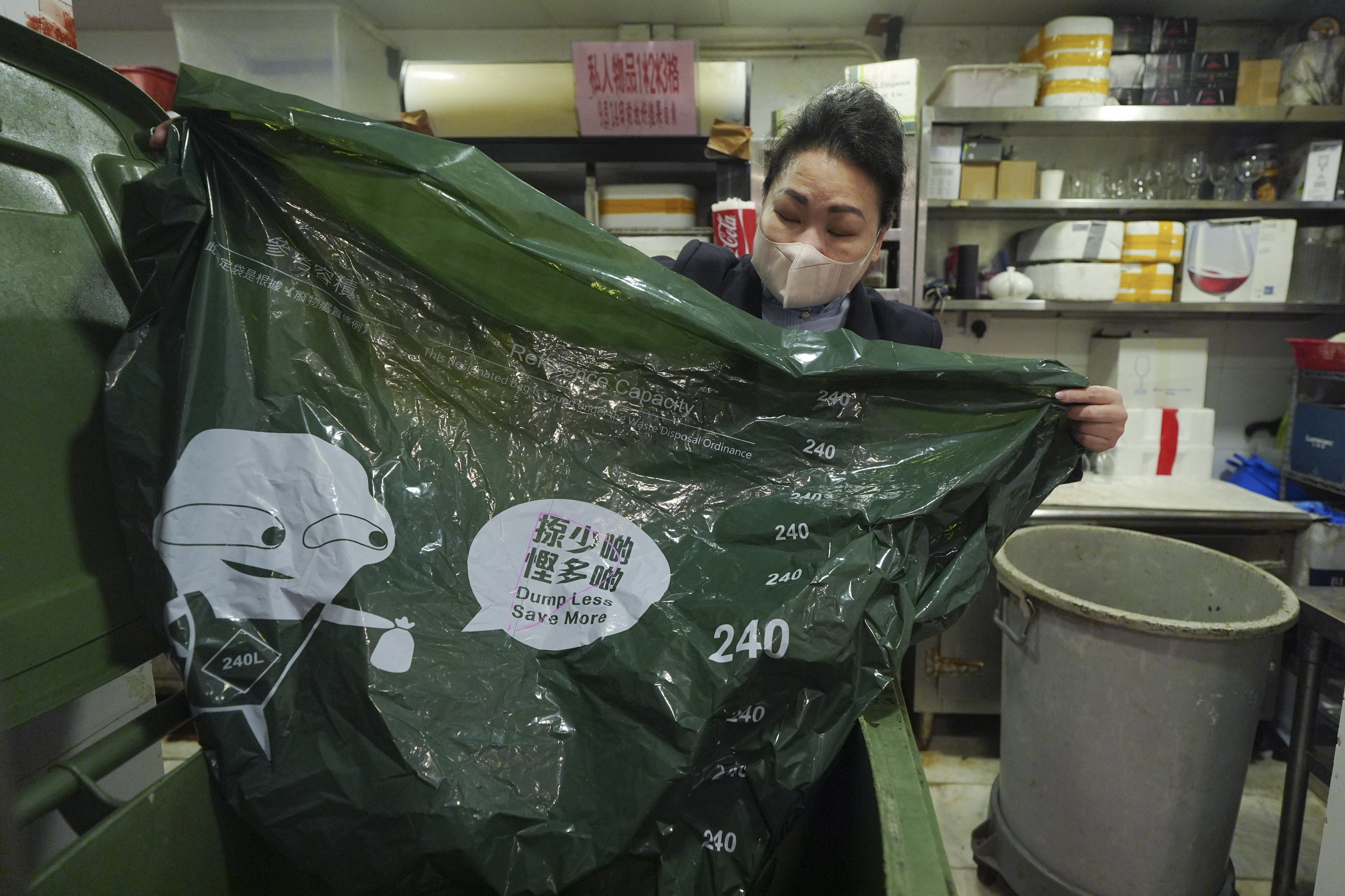 A ,member of staff at a restaurant taking part in a solid waste charging trial scheme uses one of the special plastic bags for rubbish. Photo: Eugene Lee