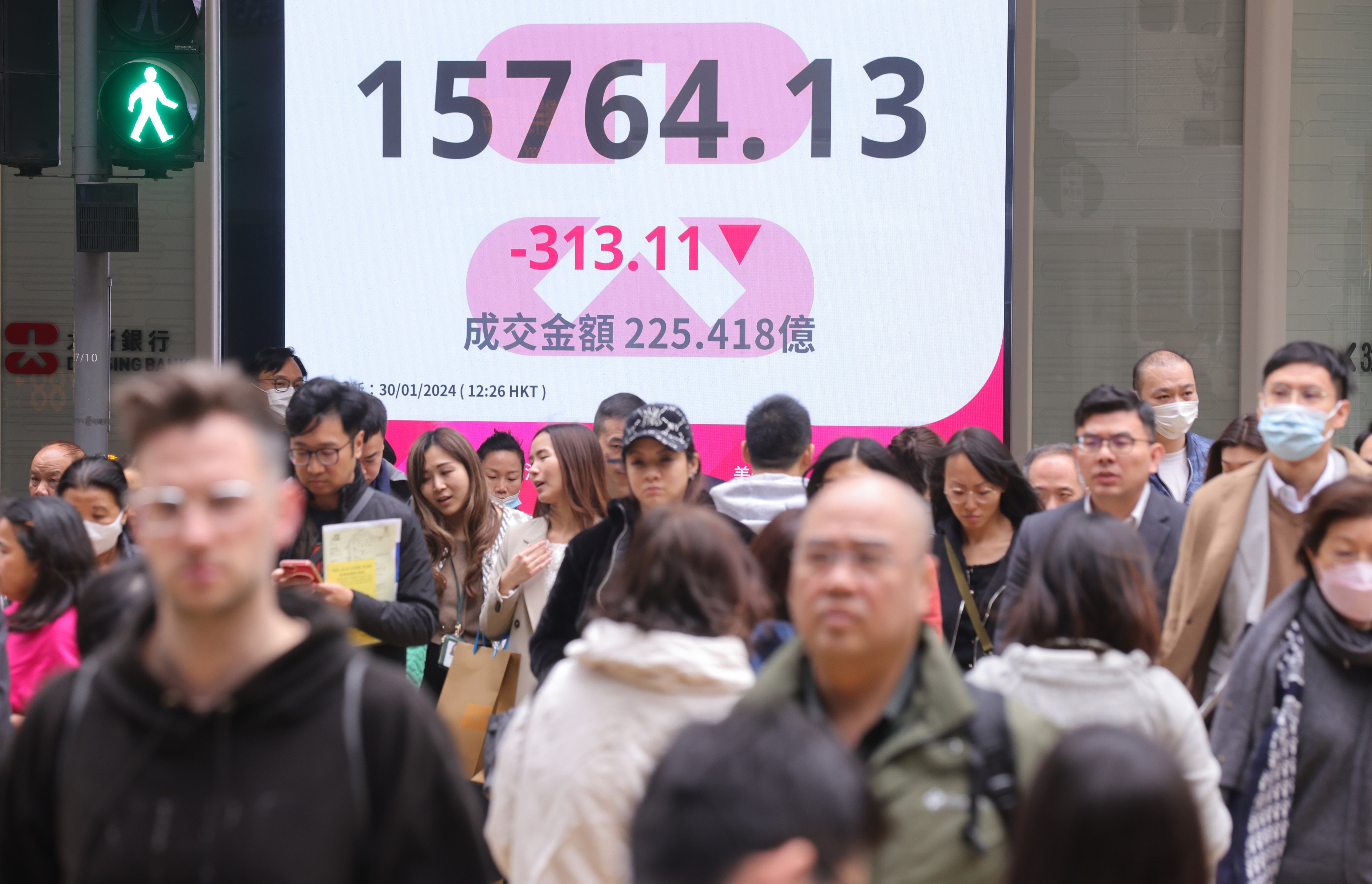 People walk past a board showing the Hang Seng Index in Central, Hong Kong, on January 20. Photo: May Tse