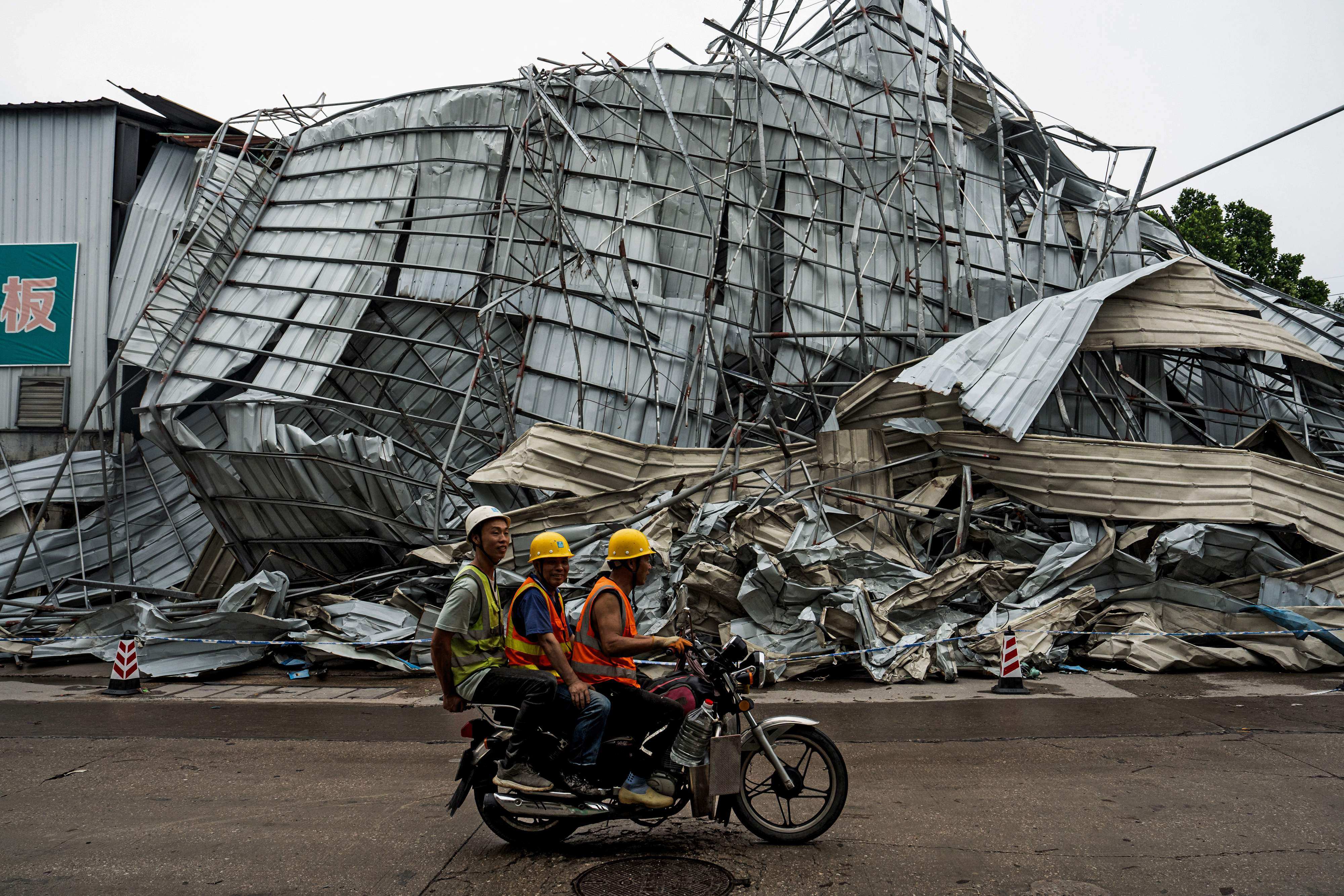 People ride past a building wrecked after a tornado hit Guangzhou, in southern China’s Guangdong province at the weekend. Photo: AFP