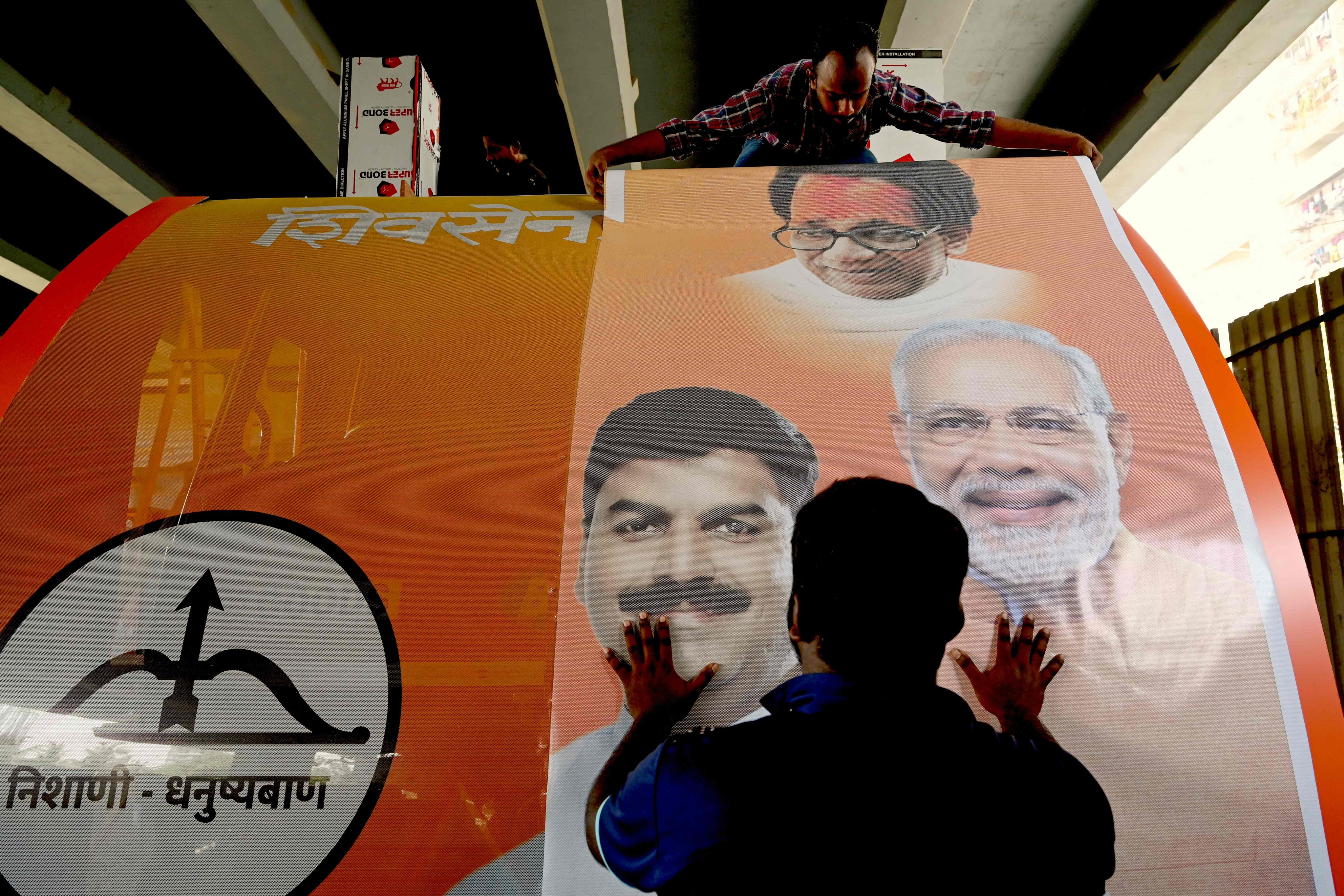 Workers fix a sticker with a photograph of BJP leader and Indian Prime Minister Narendra Modi (right) on an election campaign vehicle in Mumbai on Saturday during the ongoing Indian general election. Photo: AFP