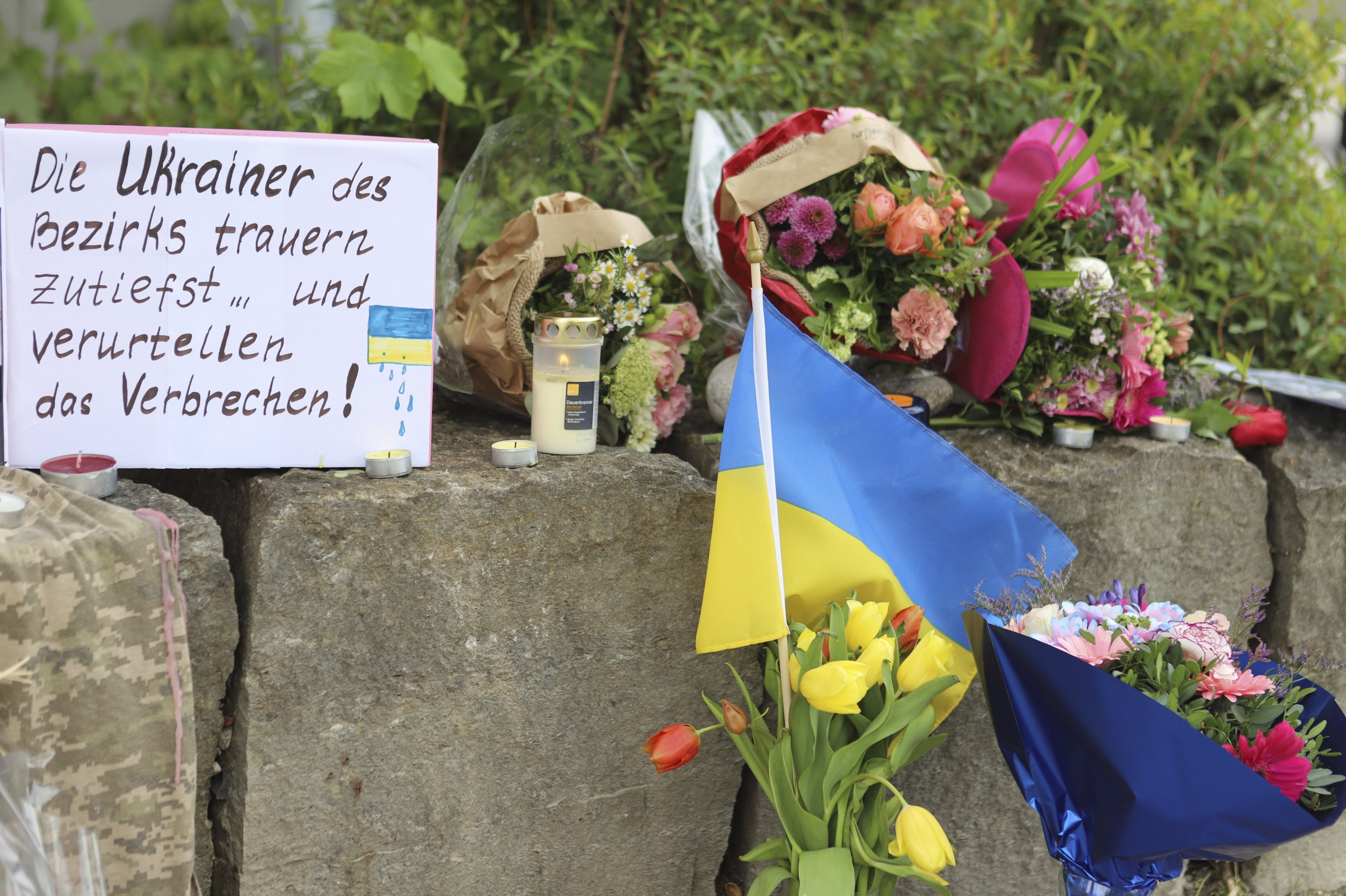 Flowers and a Ukrainian flag are laid at a shopping centre in Murnau, Germany on Sunday after two Ukrainian men were stabbed to death. A Russian suspect was arrested, German media reported. Photo: dpa via AP