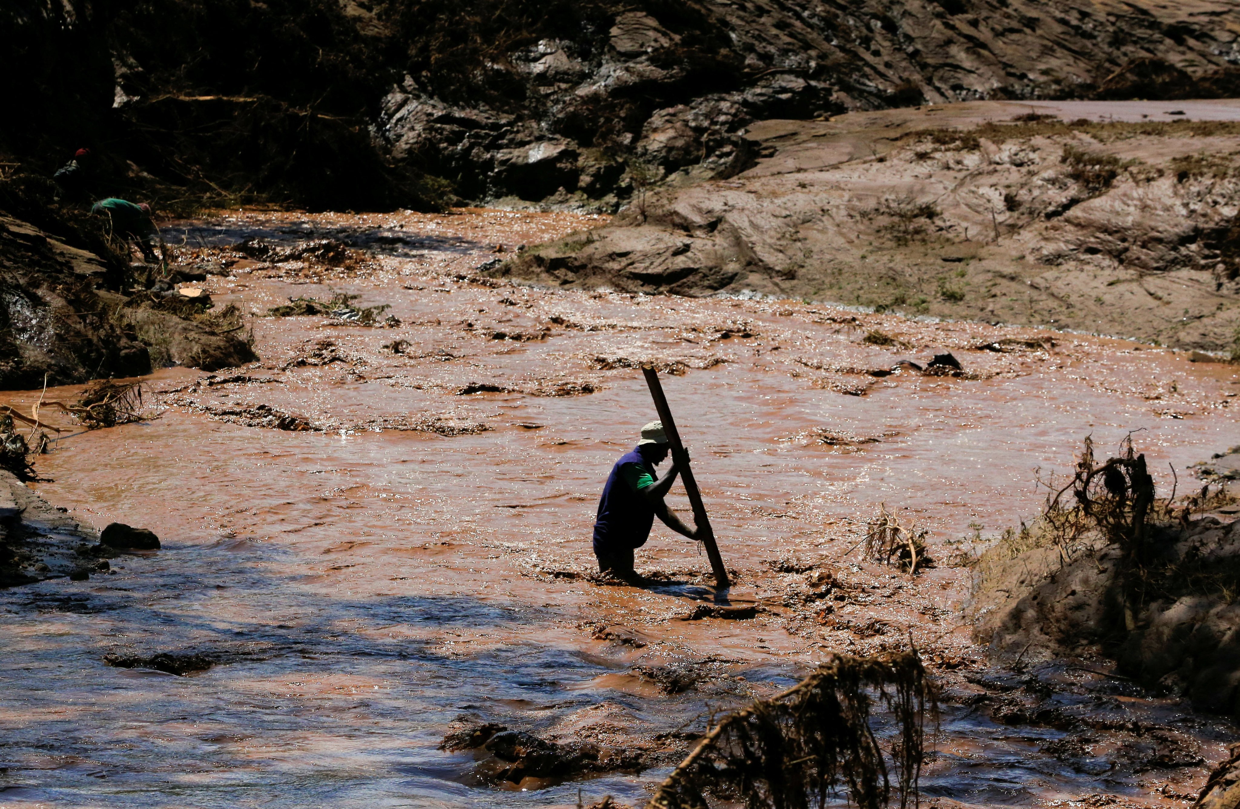 A man uses a stick to cross a river after heavy flash floods wiped out several homes when a dam burst, following heavy rains in Kenya on Monday. Photo: Reuters