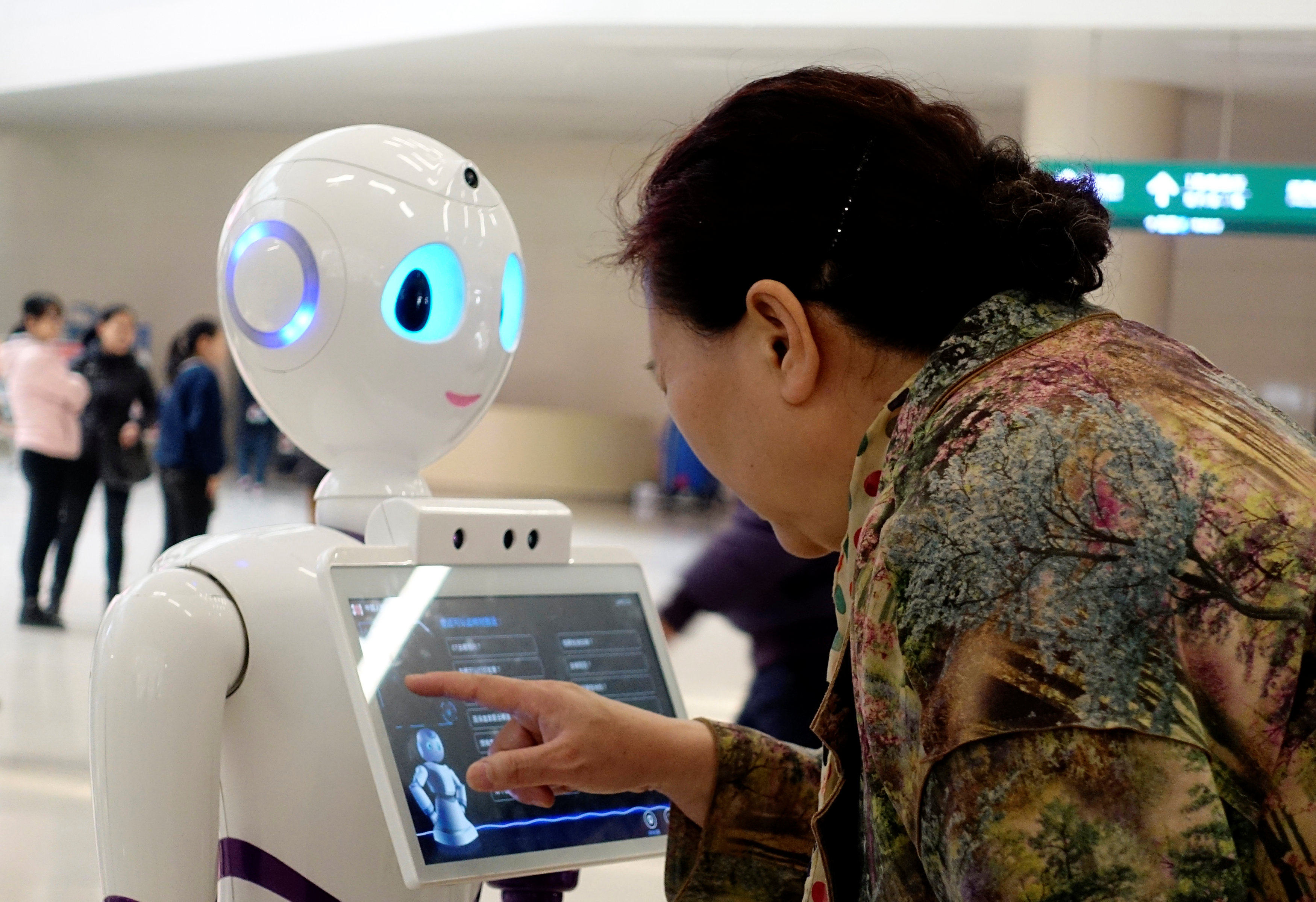 A woman touches a screen on a robot at the outpatient hall of People’s Liberation Army General Hospital in Beijing, China, on March 16, 2017. Photo: Reuters
