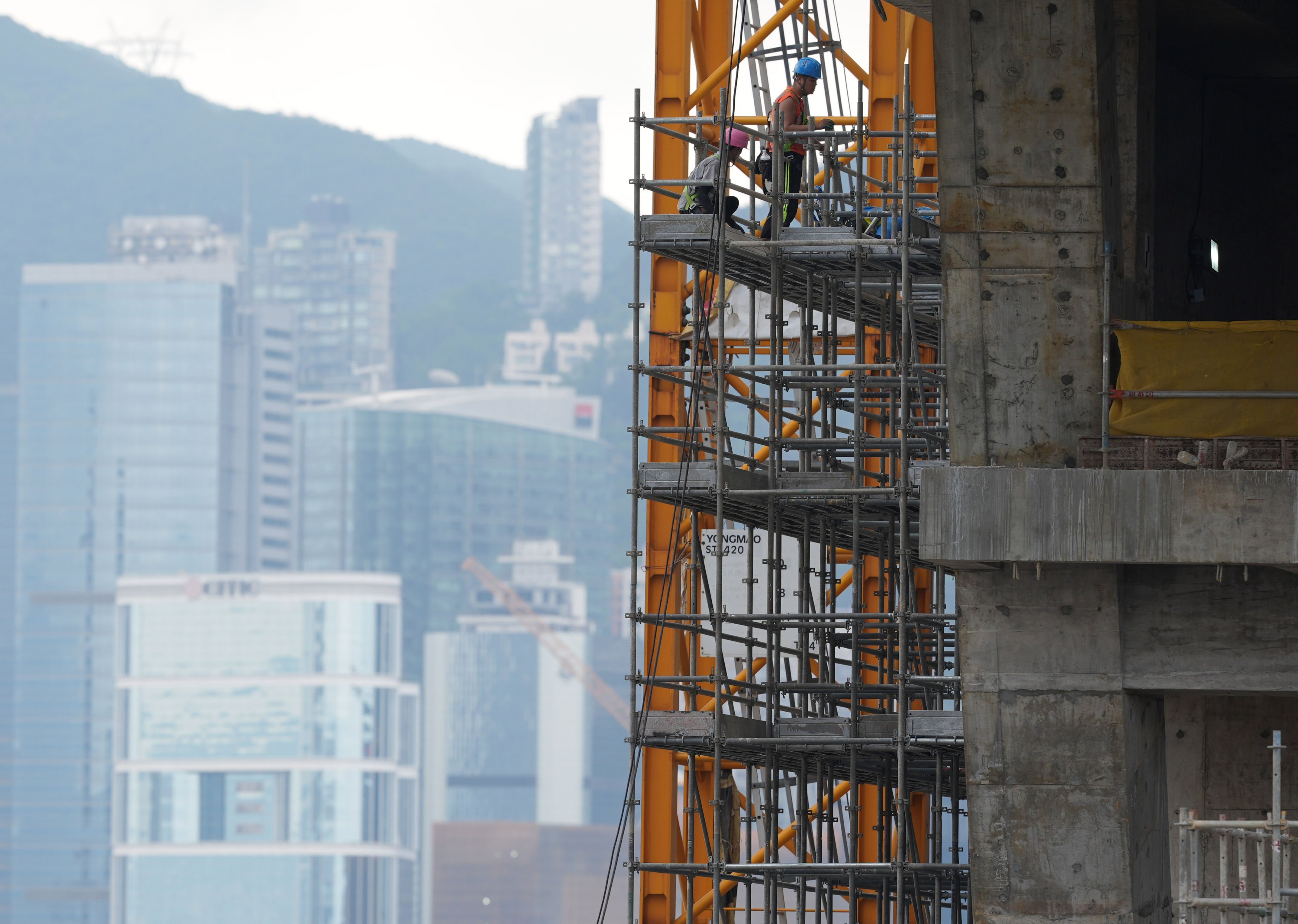Construction workers are seen on scaffolding at a construction site in the West Kowloon Cultural District on April 27. The Hong Kong Construction Association has launched a trial scheme to monitor workers’ compliance with safety measures. Photo: Eugene Lee