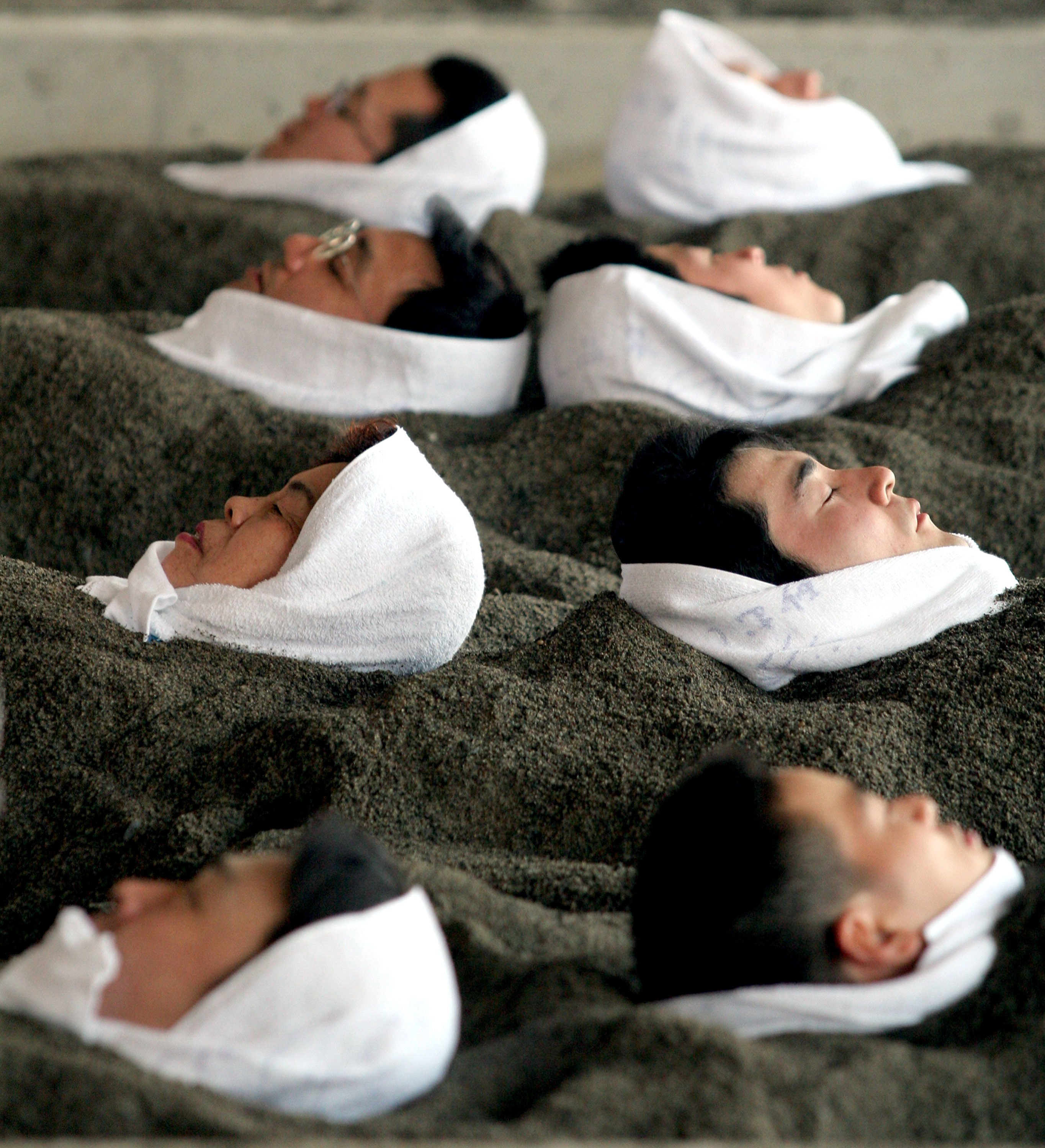 People buried up to their necks in black sand for a sand bath in Ibusuki, Kagoshima prefecture. Photo: Getty Images