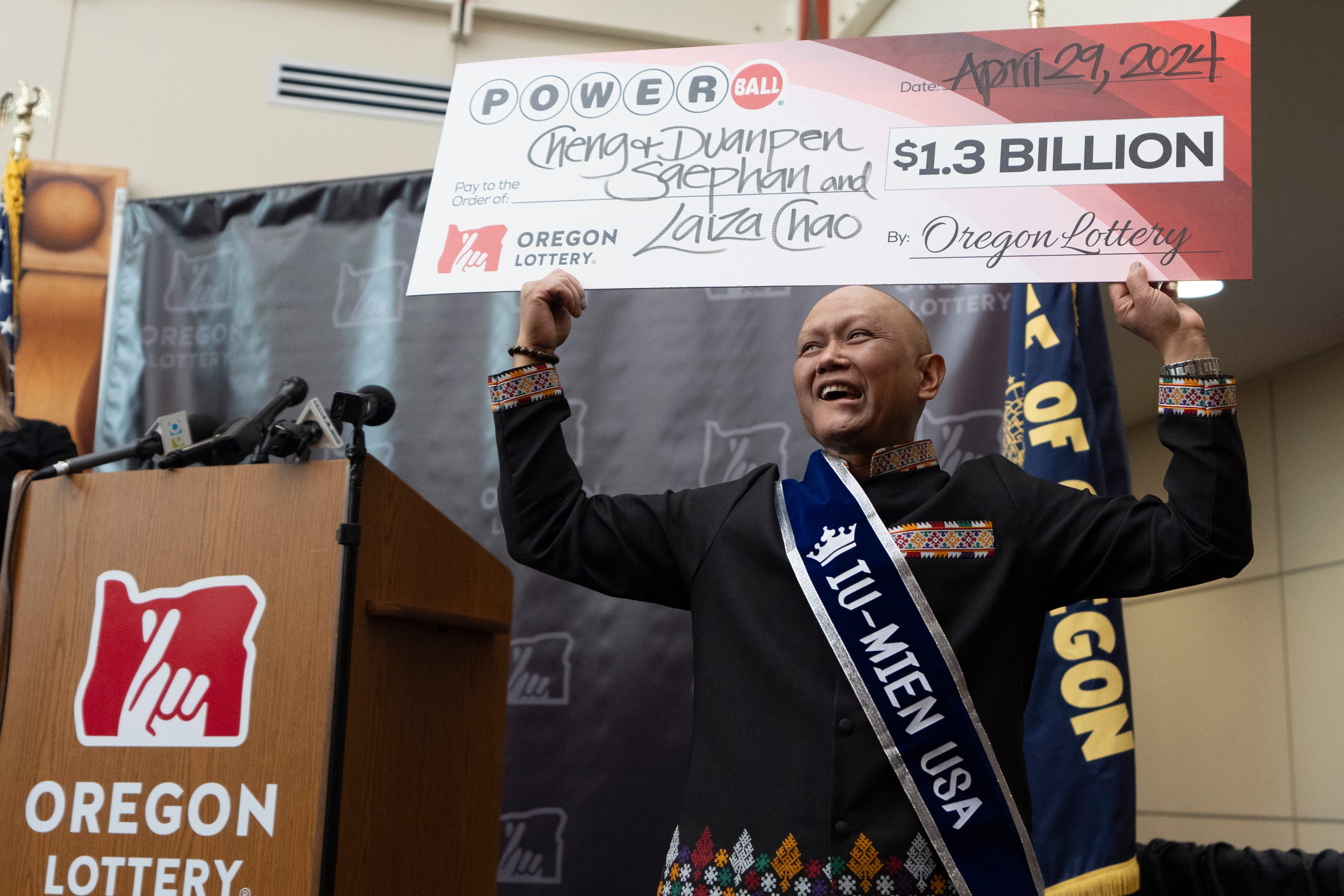 Cheng “Charlie” Saephan displays a cheque above his head after it was revealed that he was one of the winners of the $1.3 billion Powerball jackpot on Monday. Photo: AP