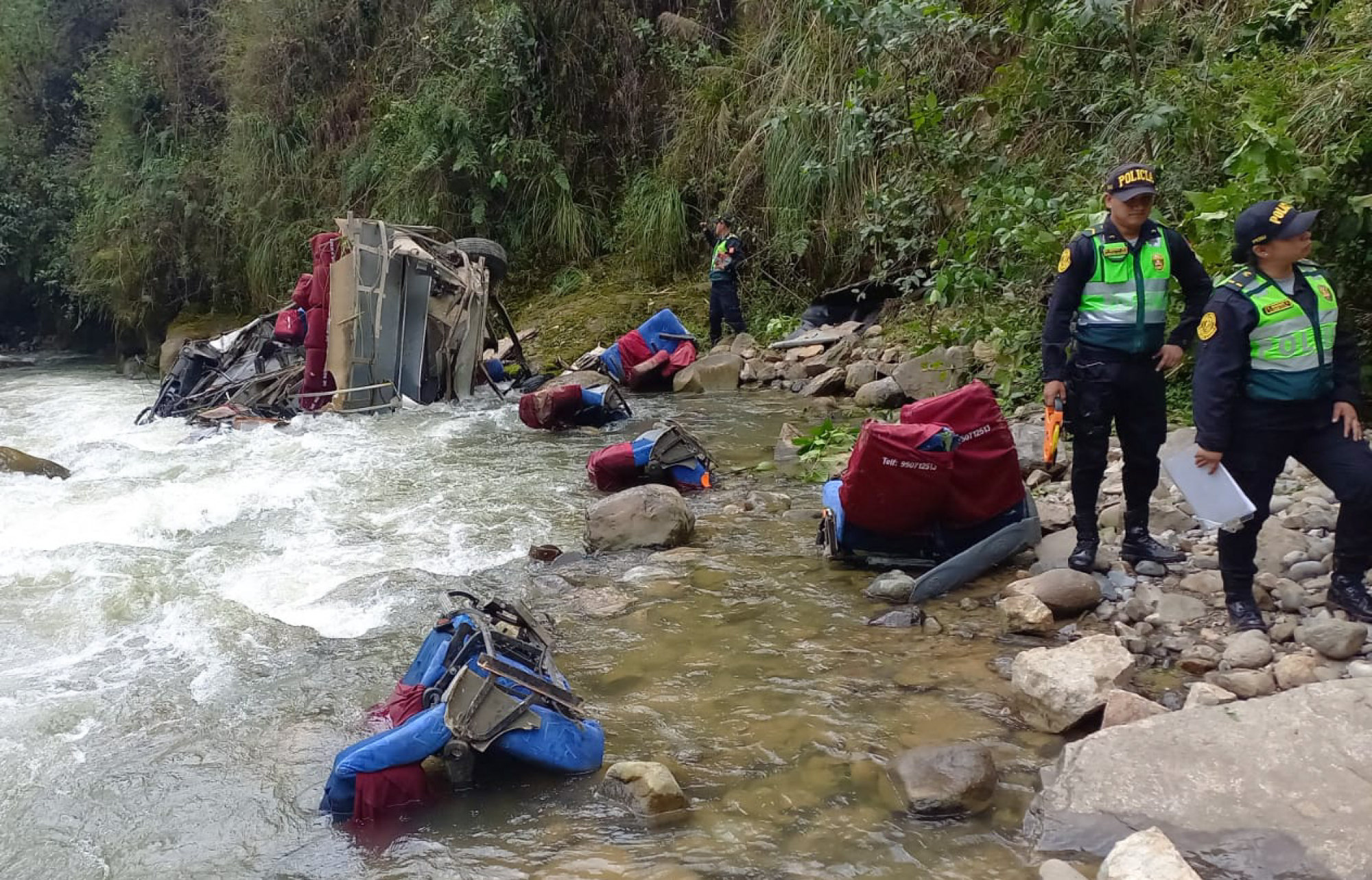 Police officers inspect the remains of a bus that plunged into a ravine from a mountain road in the Andean region of Cajamarca, Peru on Monday. Photo: Policia Nacional del Peru / AFP