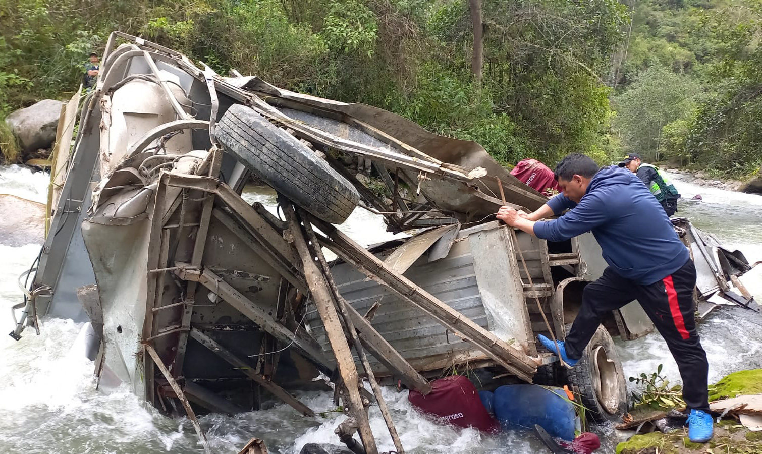 A policeman dressed as a civilian inspecting the remains of a bus that fell into a ravine from a mountain road in the Andean region of Cajamarca, Peru on Monday, leaving at least 25 dead. Photo: Policia Nacional del Peru / AFP  