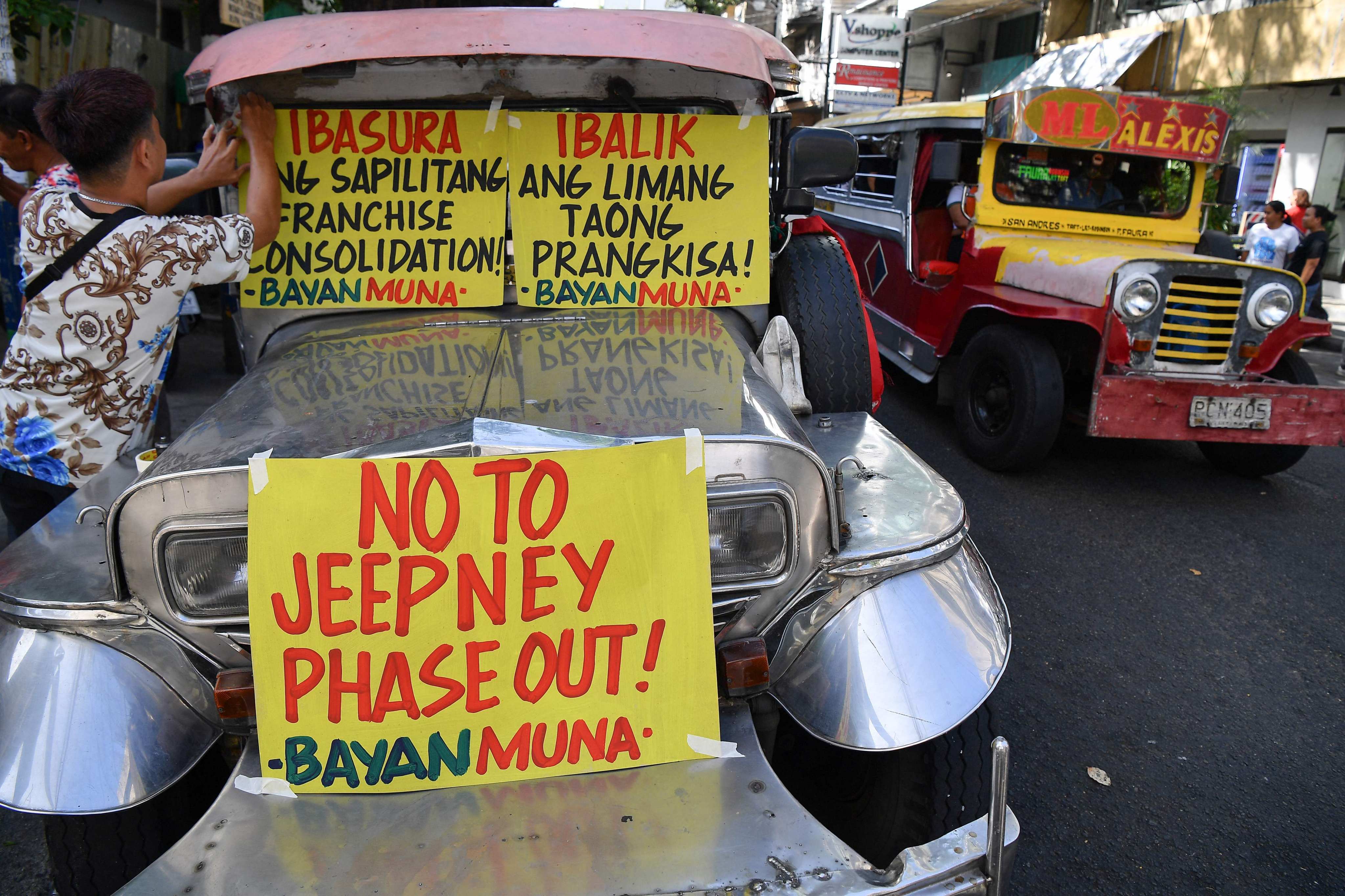 A supporter of drivers of passenger jeepneys displays a banner along a street in Manila on Monday on the first day of the jeepney strike. Photo: AFP