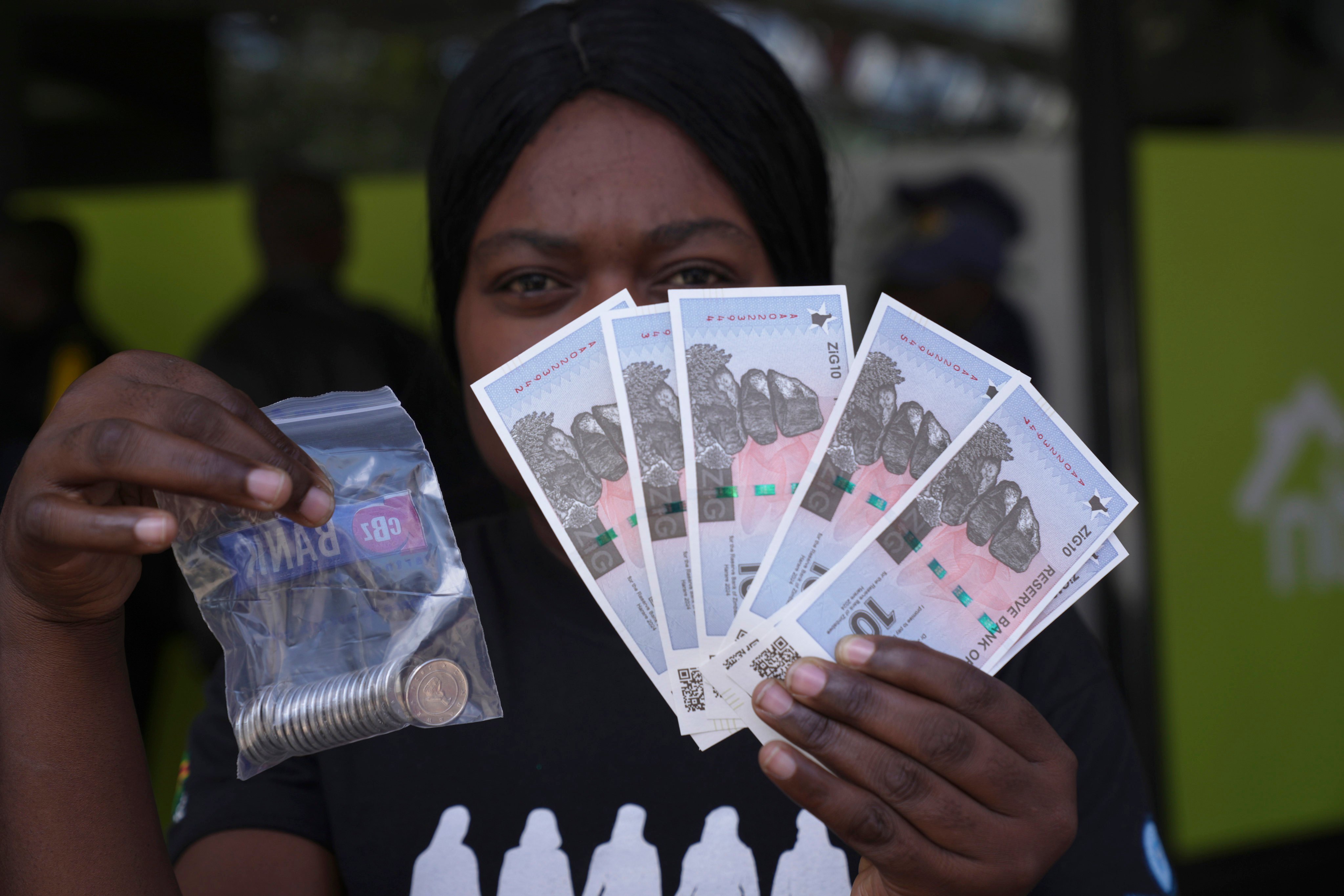 A woman holds the new Zimbabwean banknotes and coins called the ZiG. Photo: AP
