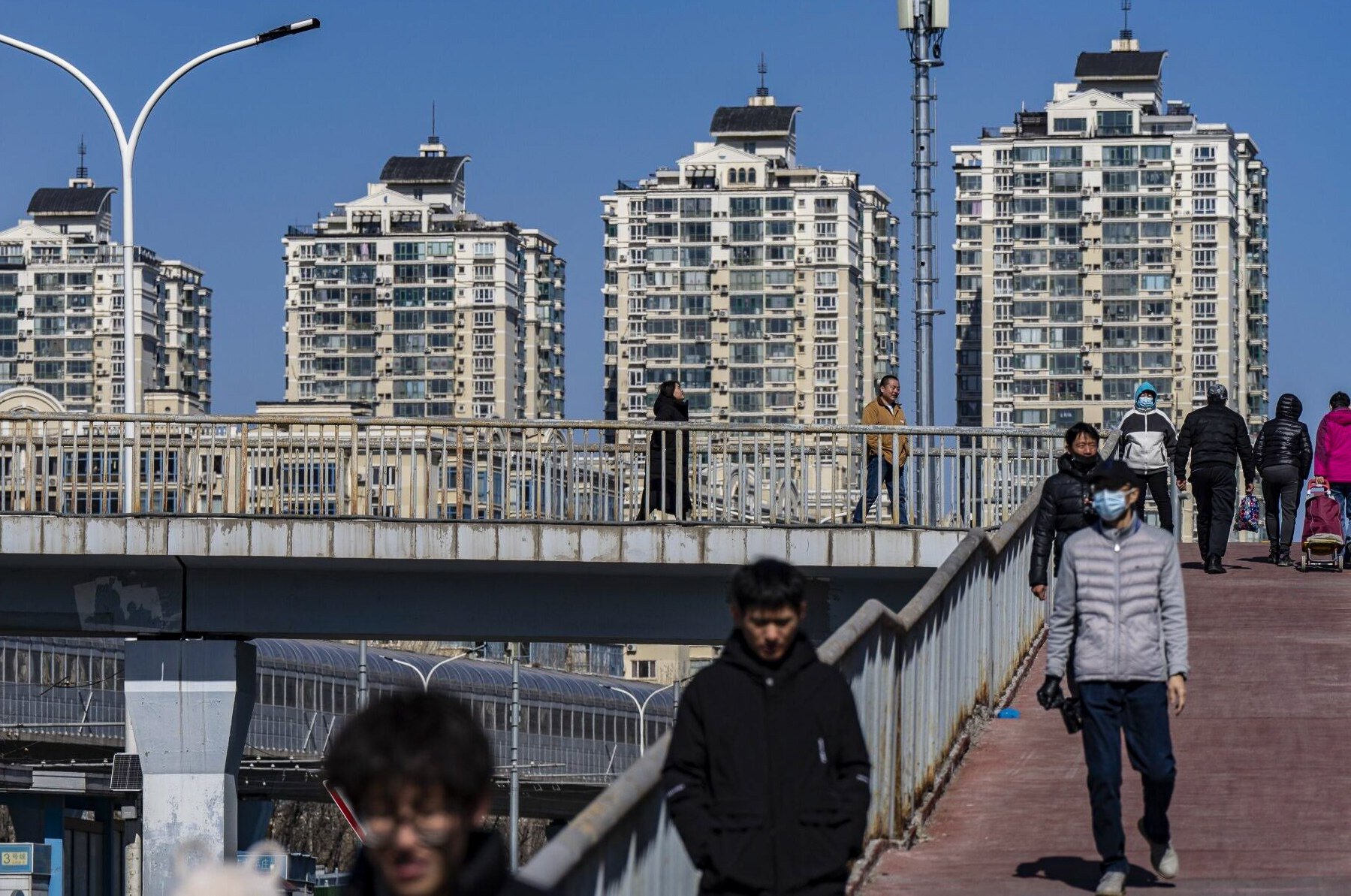 Pedestrians cross a footbridge near residential buildings in Beijing on March 3, 2024. Photo: Bloomberg
