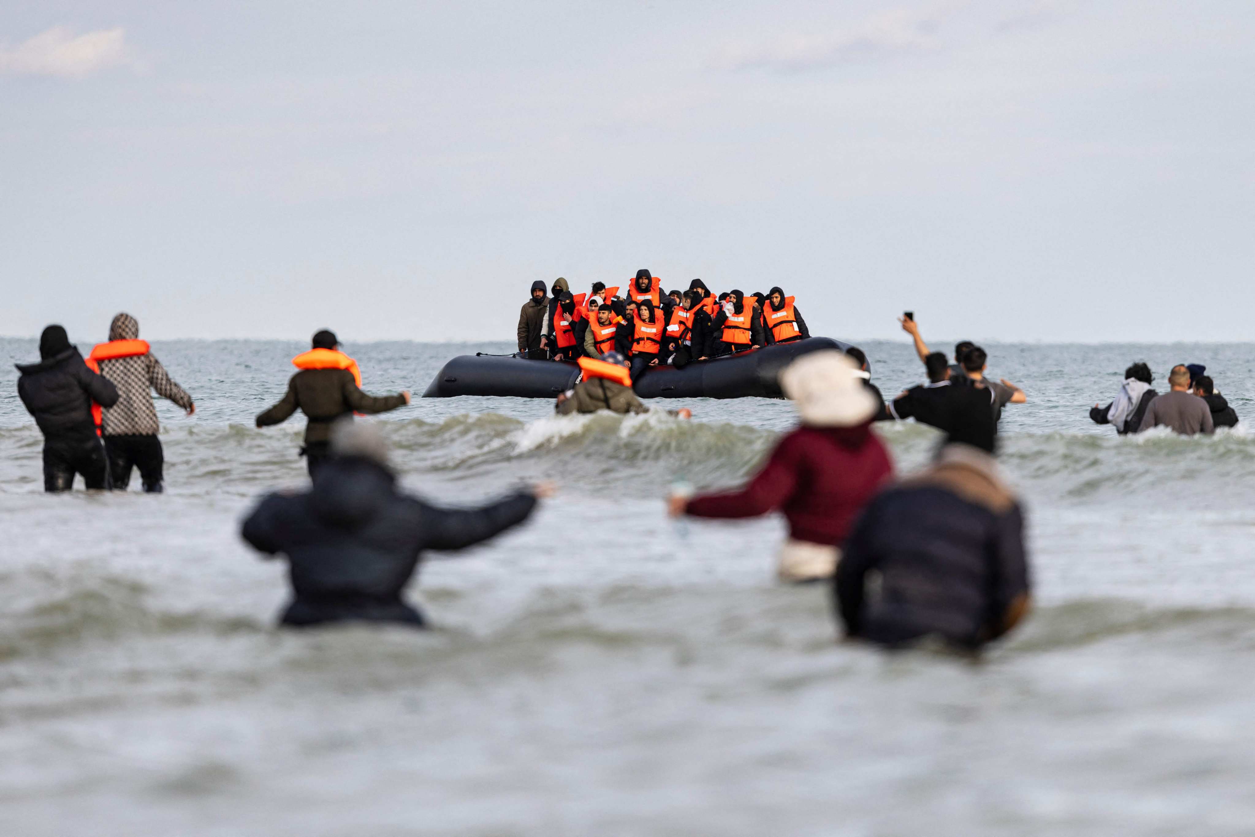 Migrants wave to a smuggler’s boat in an attempt to cross the English Channel from a beach in northern France on Friday. Photo: AFP
