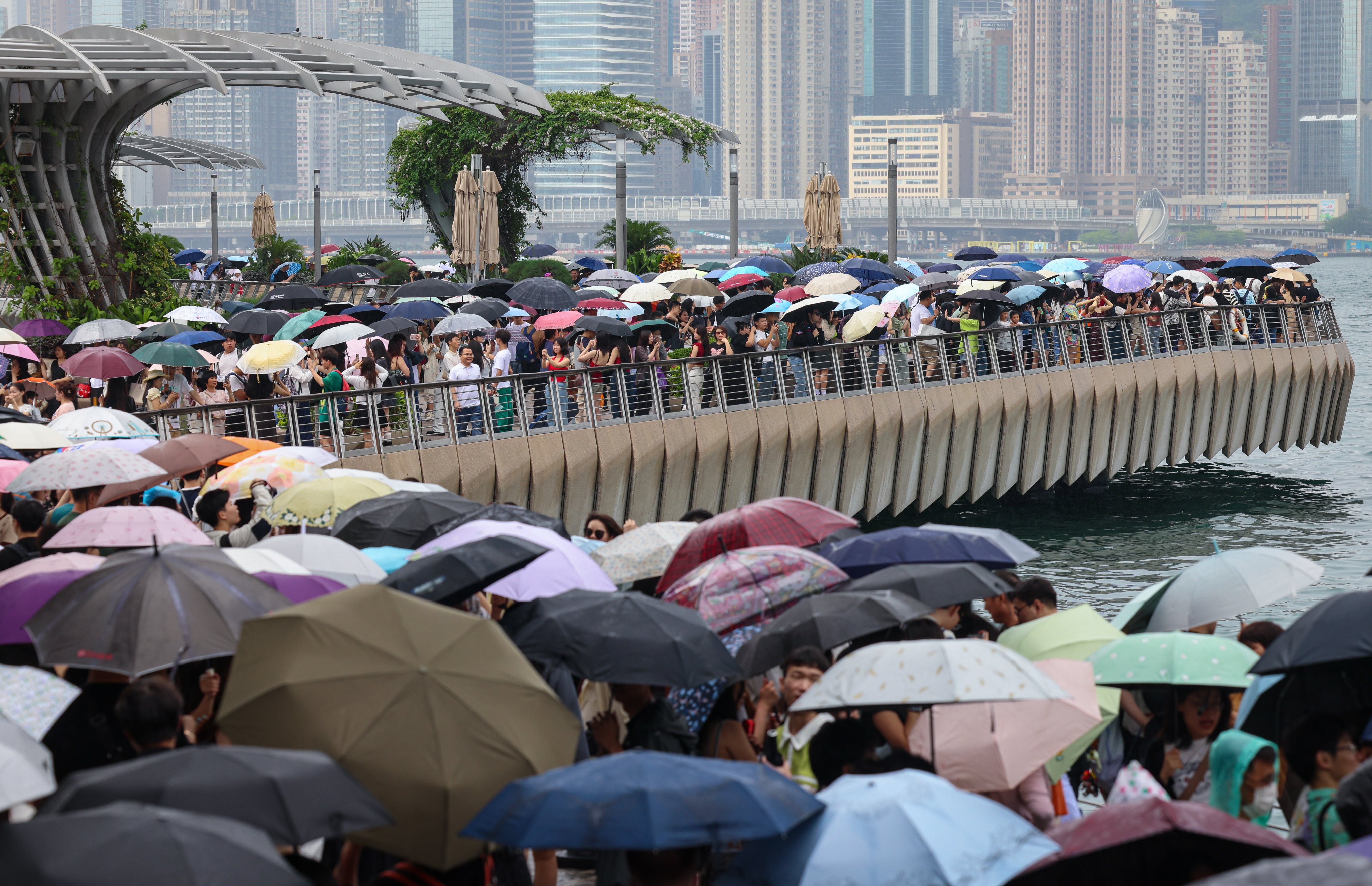 Visitors flock to the promenade overlooking Victoria Harbour in Tsim Sha Tsui despite rainy and cloudy conditions. Photo: Jelly Tse
