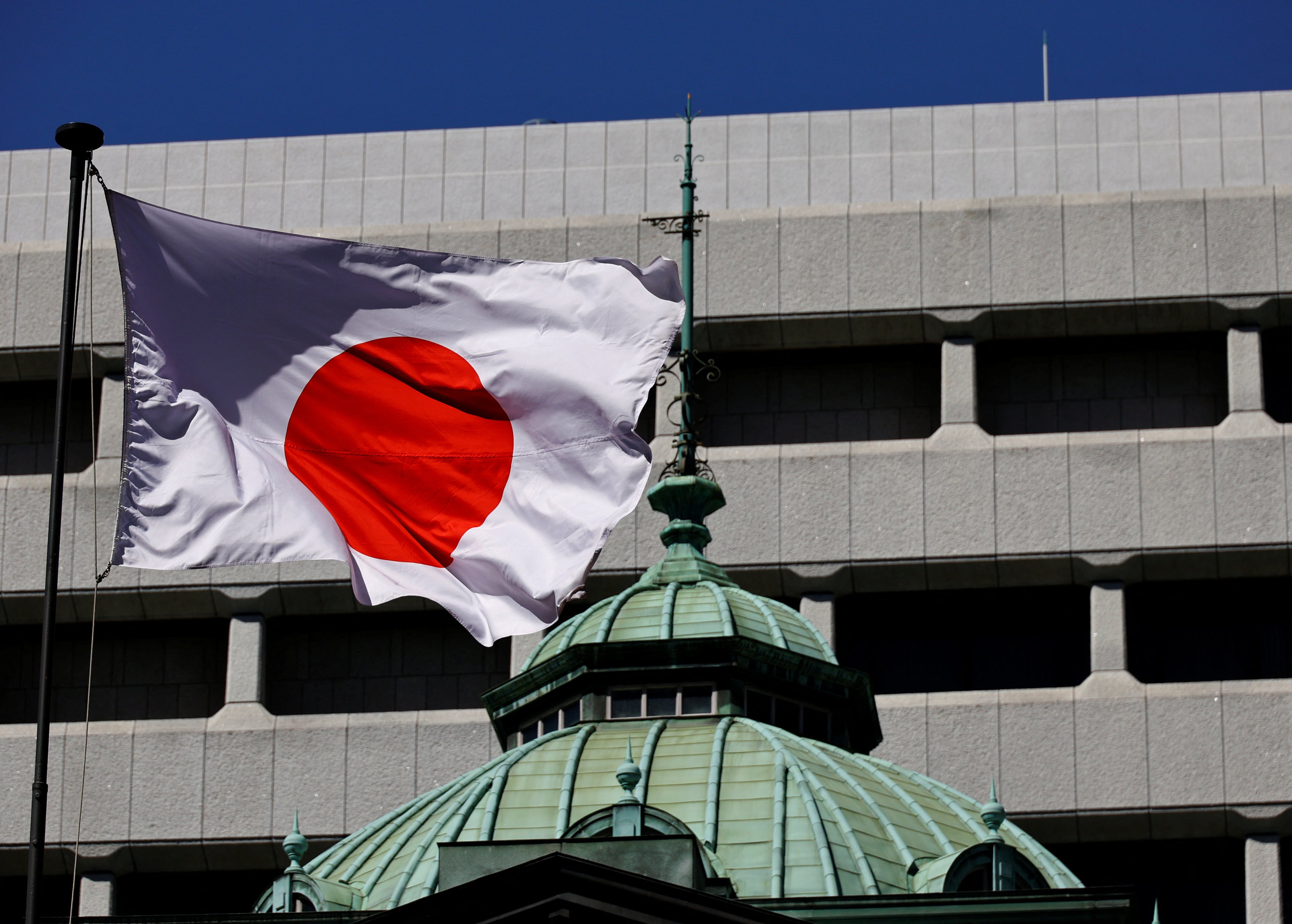 Japan’s national flag waves in the wind outside the Bank of Japan building in Tokyo. Japan’s debt-deflation lasted more than two decades, despite very low and even negative interest rates. Photo: Reuters