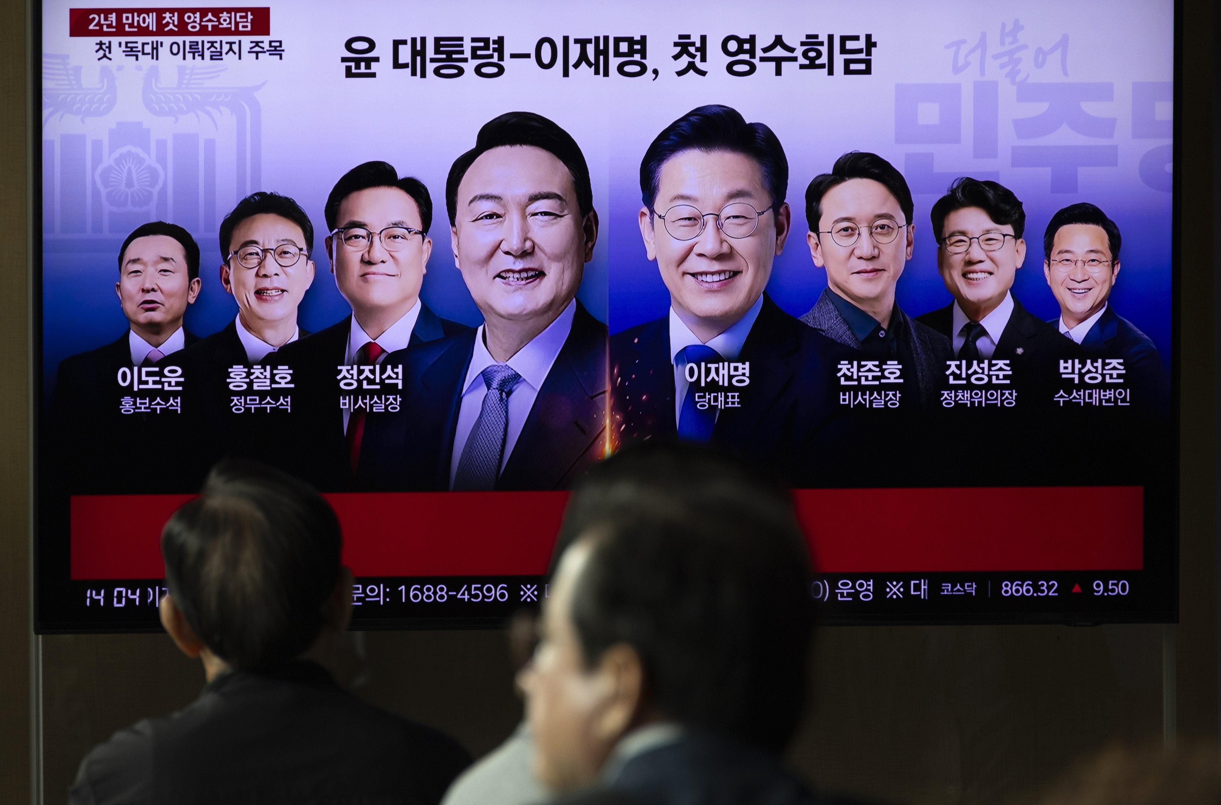 A news report about South Korean President Yoon Suk-yeol (centre, left) first-ever meeting with opposition leader Lee Jae-myung (centre, right) is seen  on a television screen at a railway station in Seoul on Monday. Photo: EPA-EFE