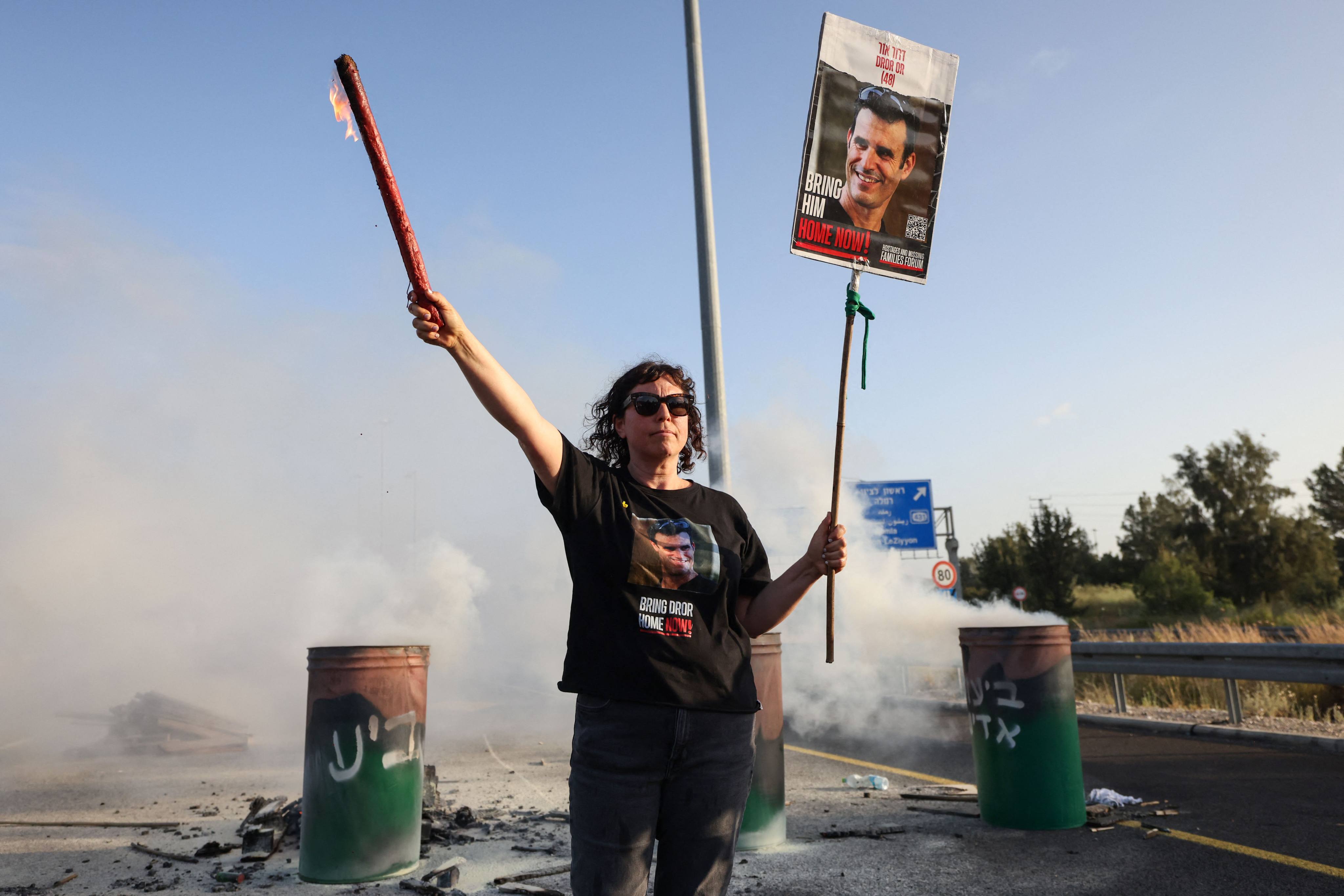 A protester holds a poster bearing the image of Israeli hostage Dror Or on the Ayalon highway between Tel Aviv and Jerusalem in April. Photo: AFP