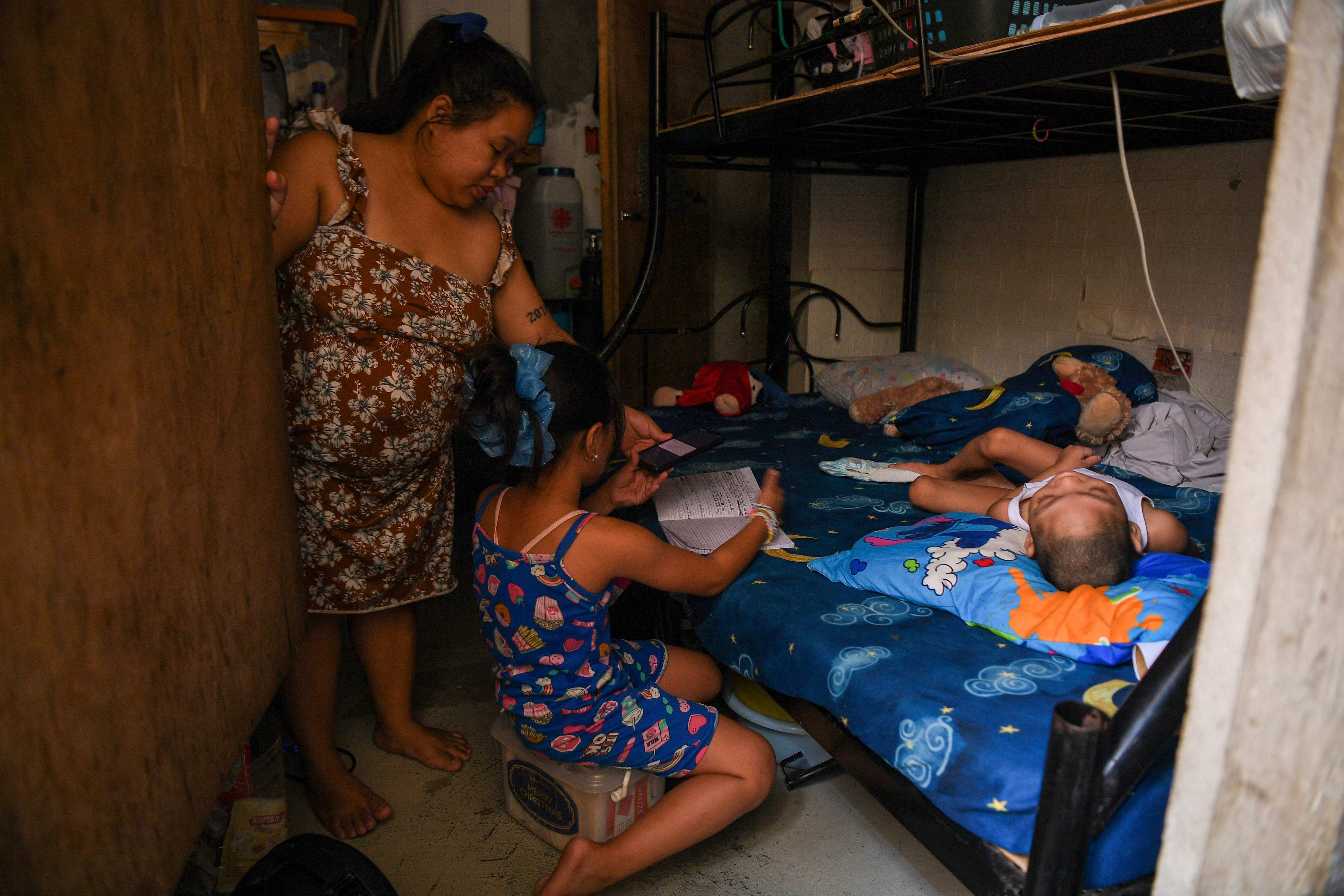 Cindella Manabat (L) helps her daughter Ella Araza (C) with her homework at their house in Manila. The Philippines shut down more than 47,000 schools nationwide due to the heat. Photo: AFP