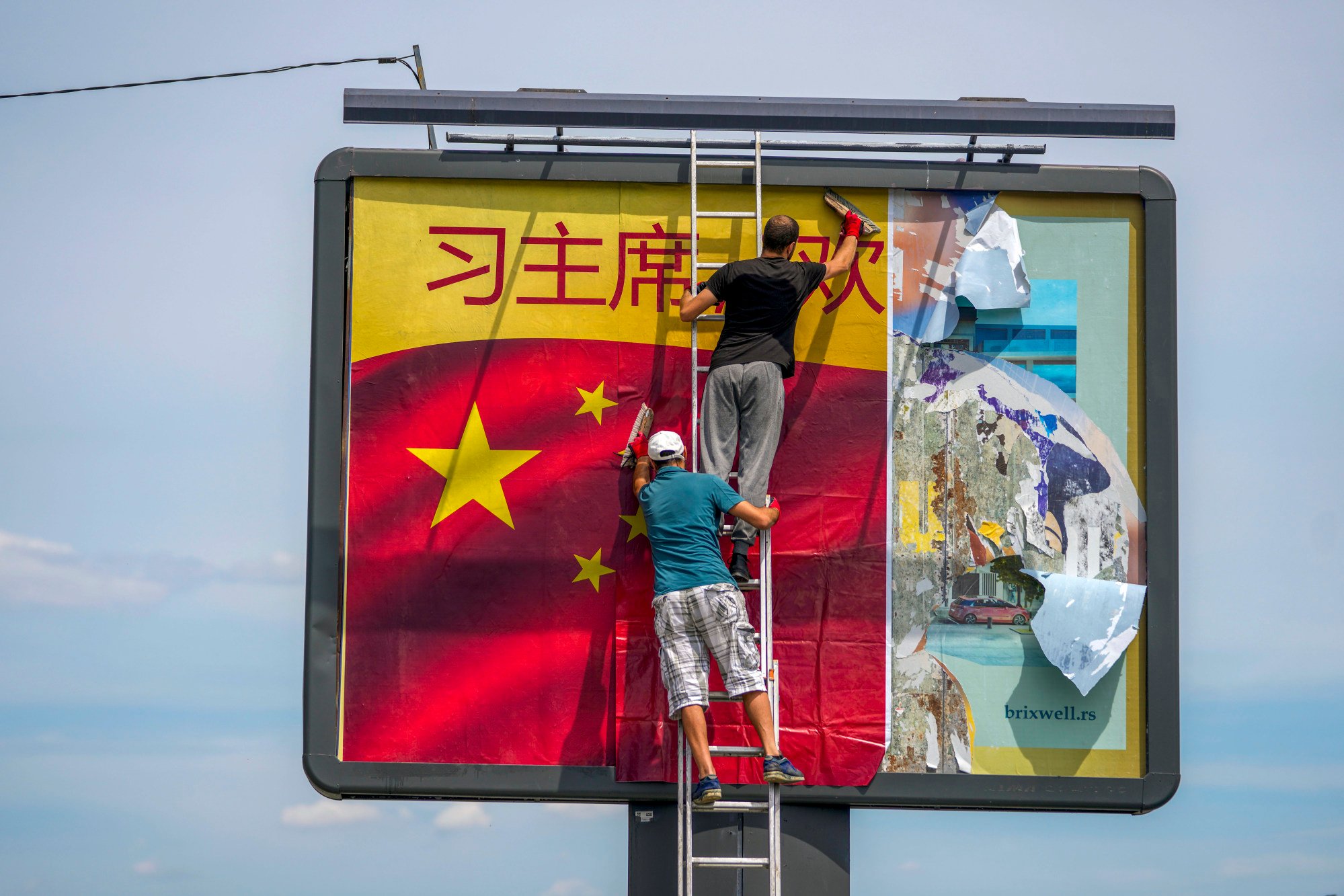Workers install a Chinese flag on a billboard in Belgrade ahead of Xi Jinping’s visit. Photo: AP