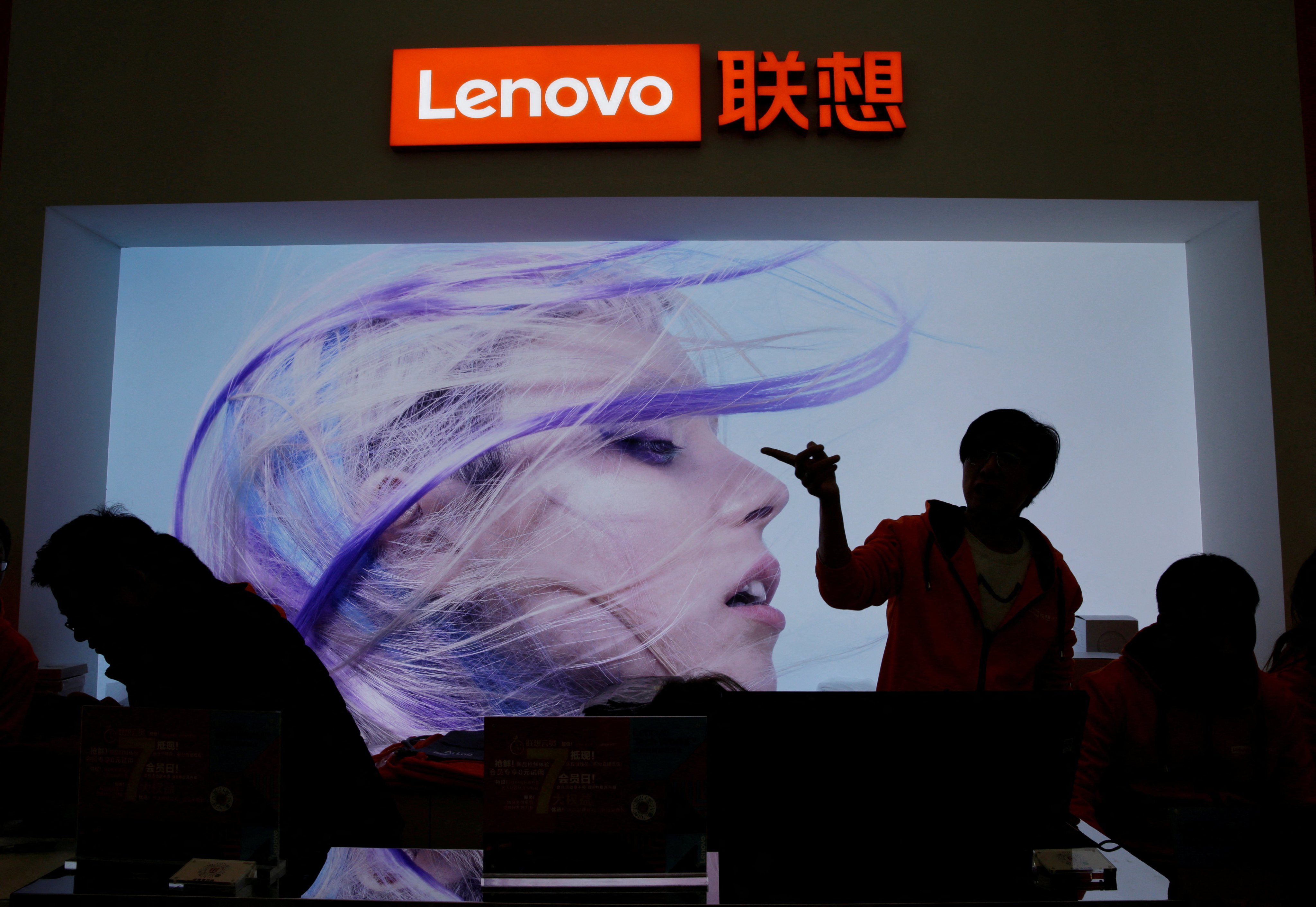 An employee gestures next to a Lenovo logo at Lenovo Tech World in Beijing, China, November 15, 2019. Photo: Reuters