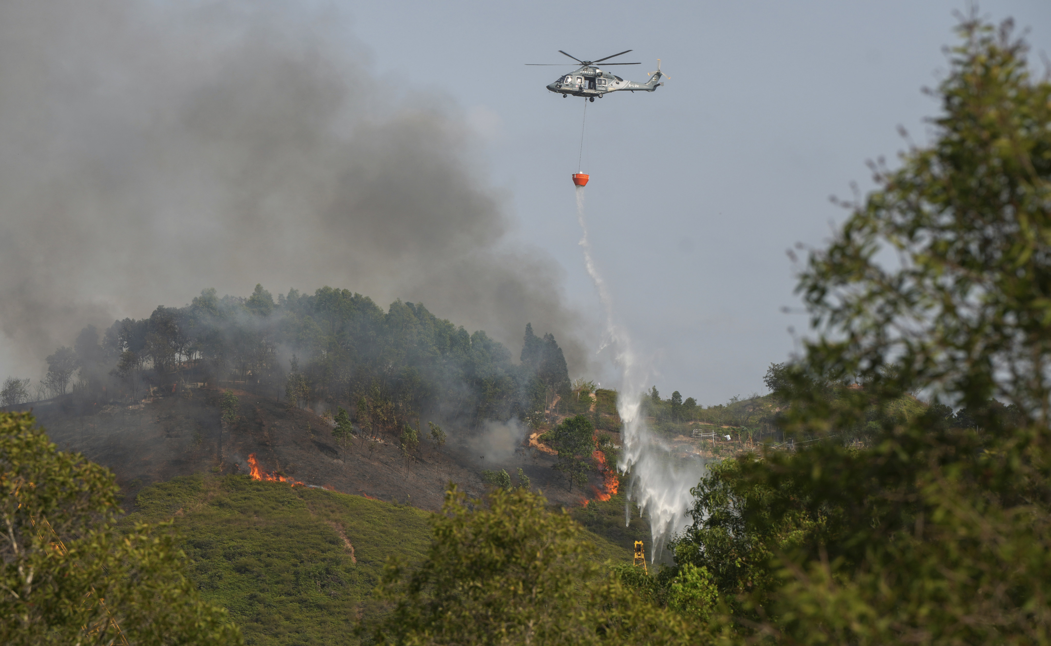 A Government Flying Service helicopter drops water on a hill fire in Yuen Long in March. Photo: Sam Tsang