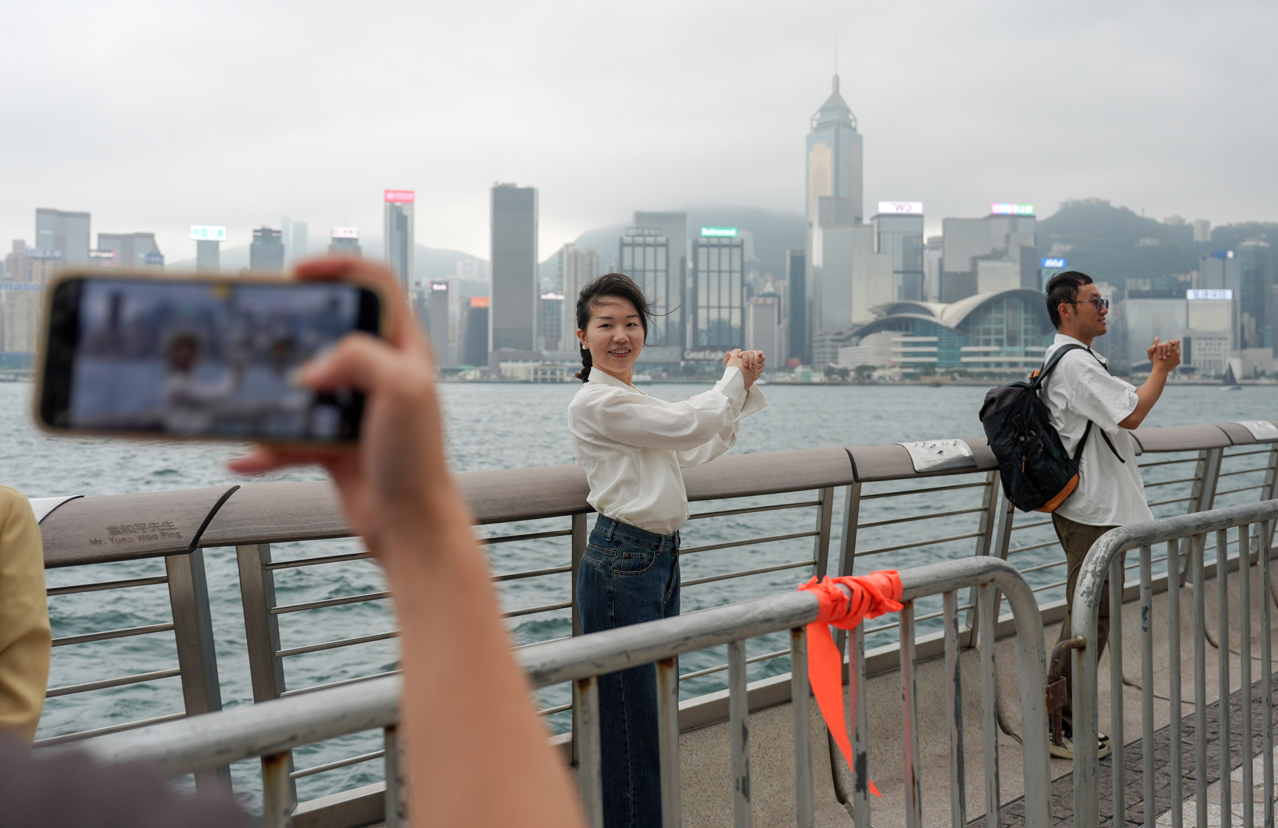 A mainland tourists strikes a pose imitating Hong Kong tycoon Li Ka-shing at the Tsim Sha Tsui waterfront on the second day of the ‘golden week’ holidays despite rain and wind. Photo: Eugene Lee