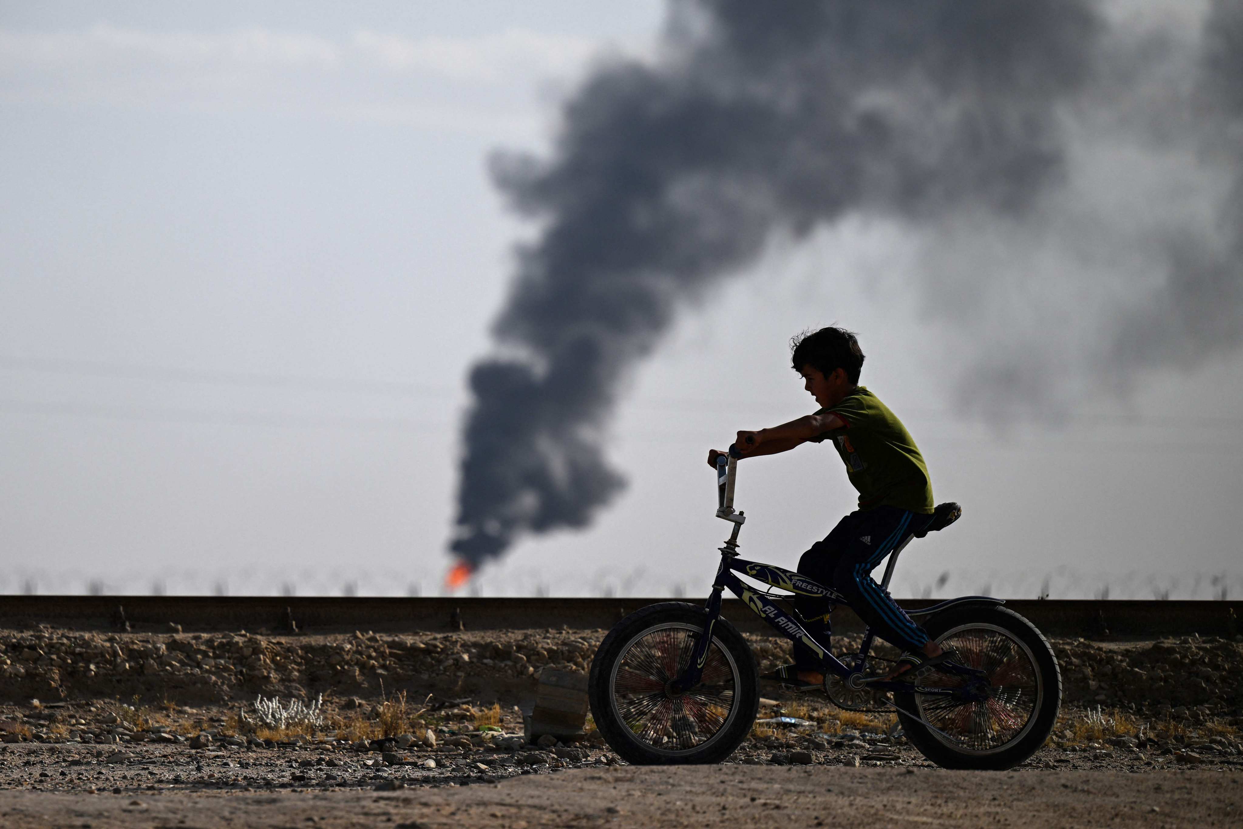 An Iraqi youth rides past a flare stack in the Rumaylah oil field near Iraq’s southern port city of Basra. Plans for the Iraq Development Road include the export of Iraqi gas to Turkey, and onwards to Europe, by a pipeline along the road. Photo: AFP