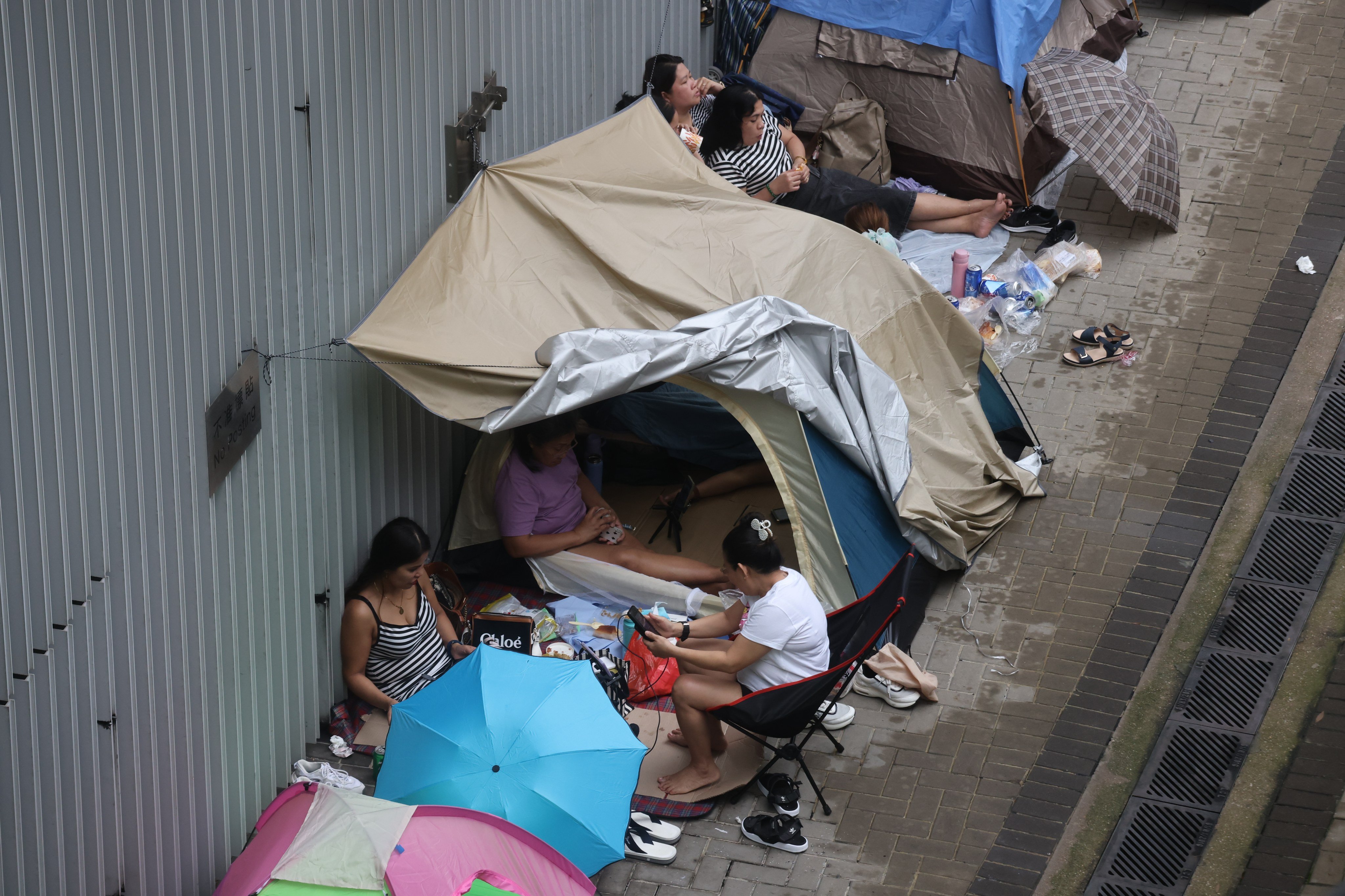 Domestic workers take shelter from the rain during their day off on April 28. Government policies aimed at restricting job-hopping by domestic workers run the risk of forcing them to stay in abusive situations instead of seeking help. Photo: Jonathan Wong