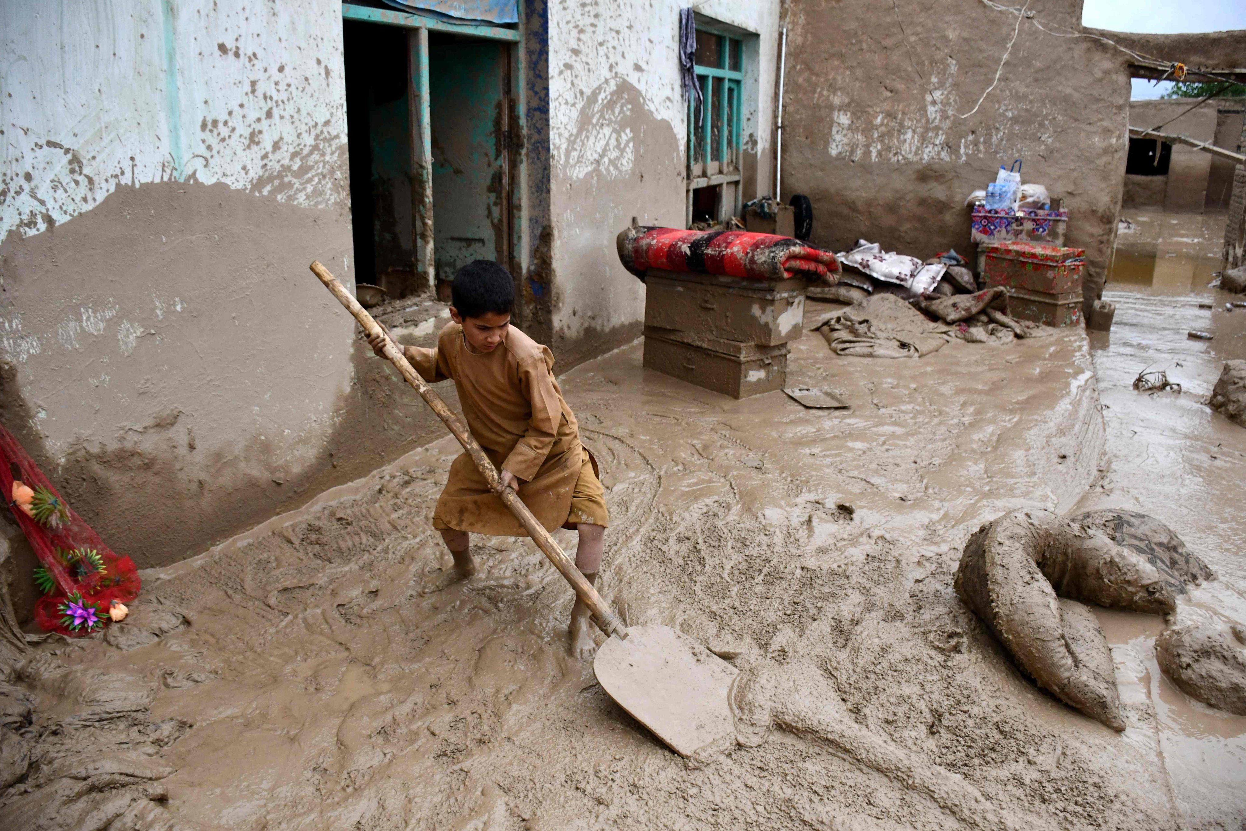 An Afghan boy shovels mud from the courtyard of a house in the Baghlan-e-Markazi district of Baghlan province. Hundreds of people are thought to have died in the nation after flash floods on Friday. Photo: AFP