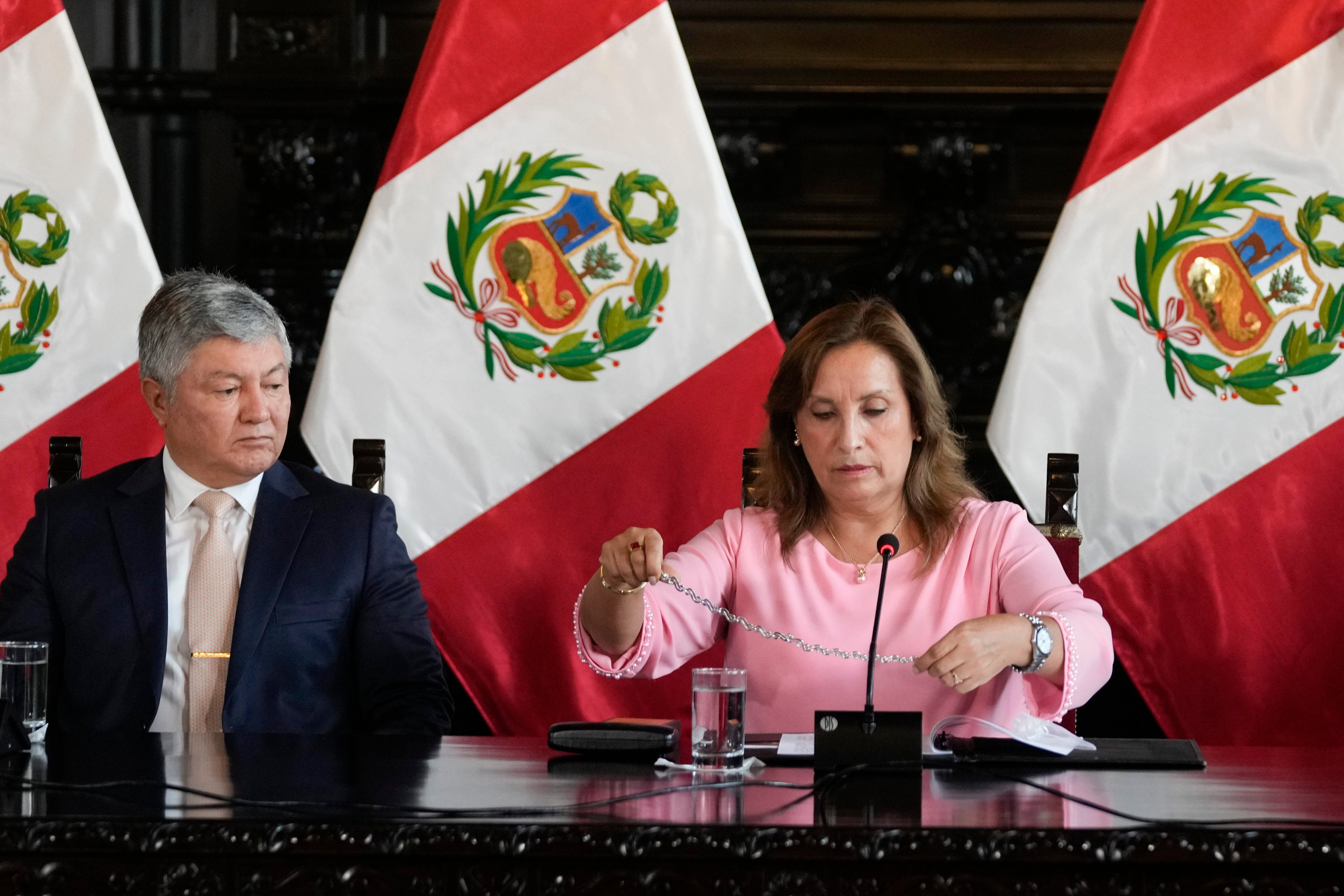 Peruvian President Dina Boluarte, accompanied by her lawyer Mateo Castaneda, shows her necklace to the media at the government palace in Lima in April amid an investigation into whether she illegally received cash, luxury watches and jewellery. Photo: AP