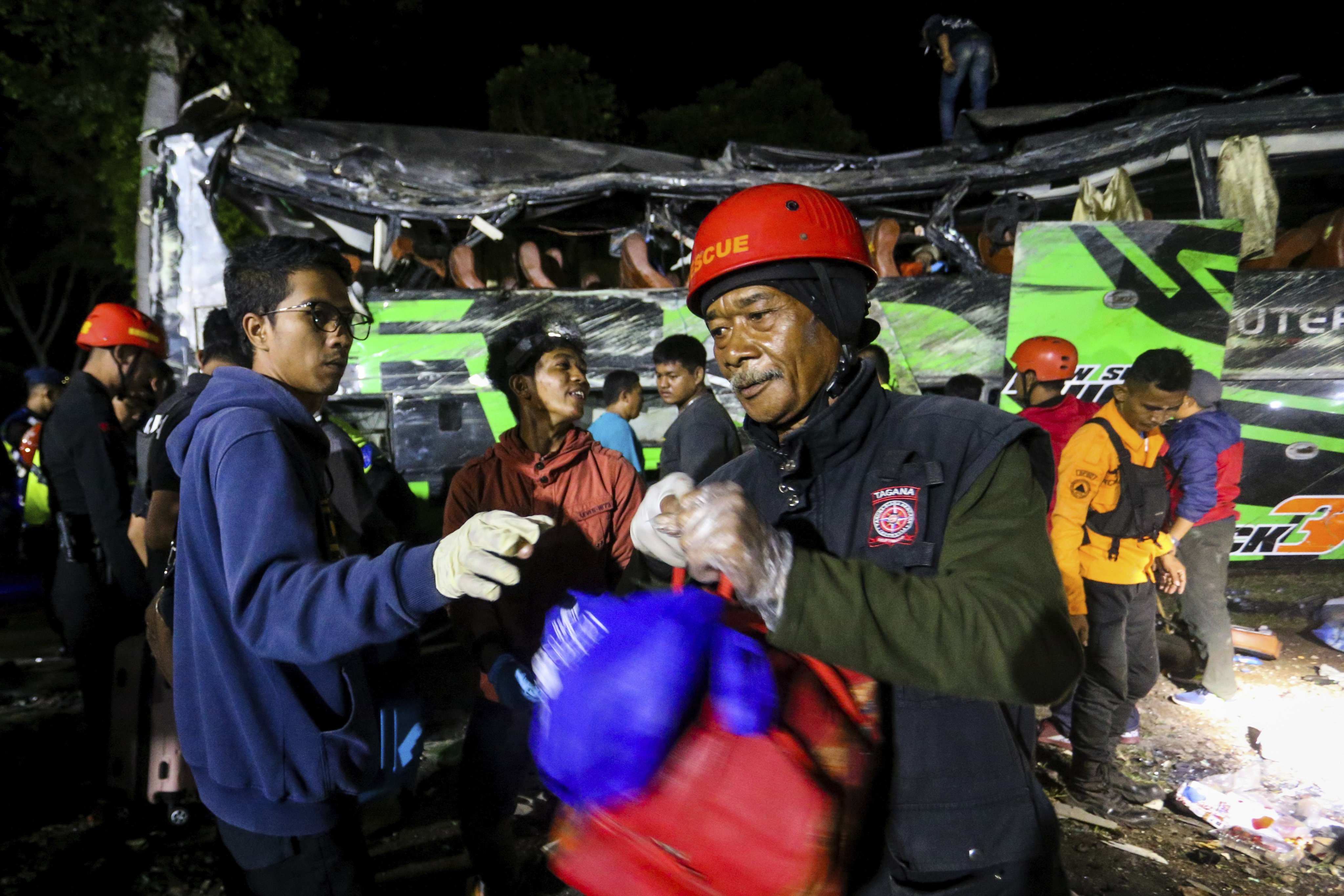 Rescuers collect the belongings of victims from the wreckage of a bus carrying students after it crashed late on Saturday in Subang, West Java, Indonesia. Photo: AP