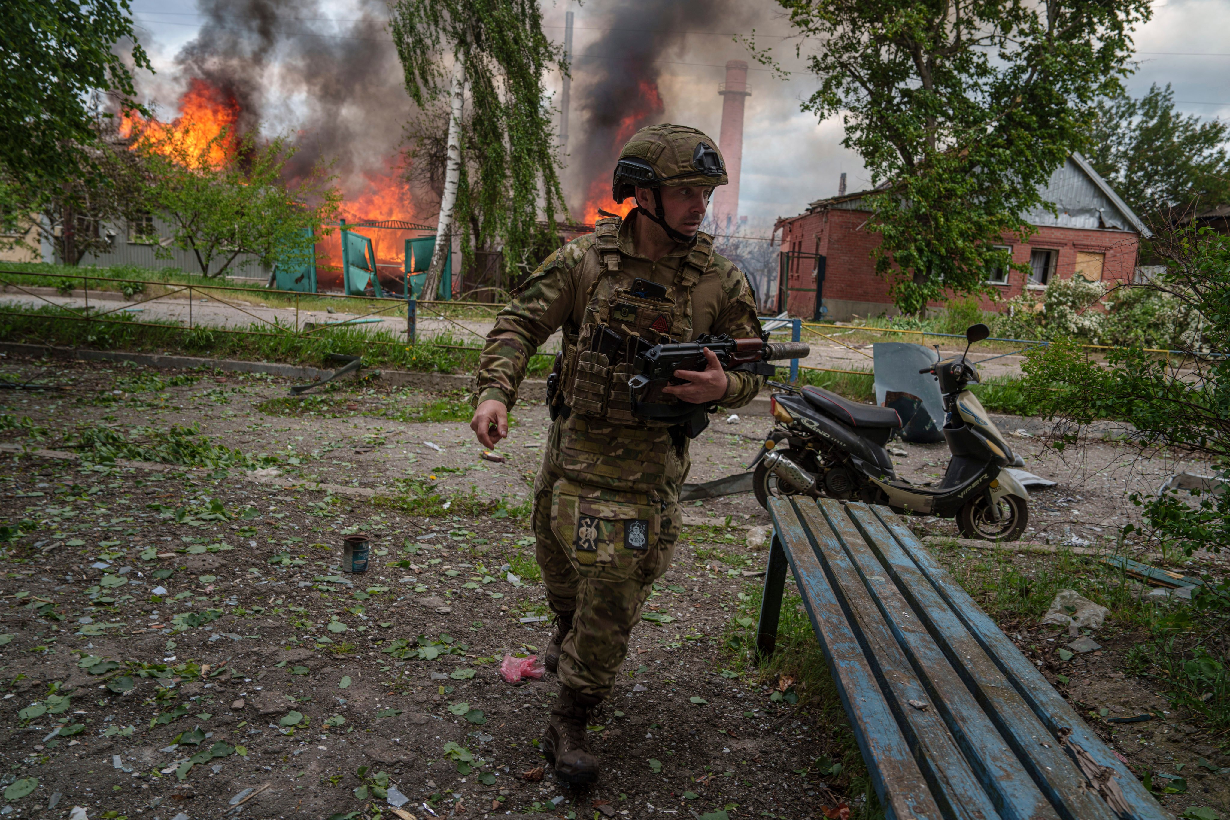 A police officer near a burning house destroyed by a Russian air strike in Vovchansk, Ukraine. Photo: AP