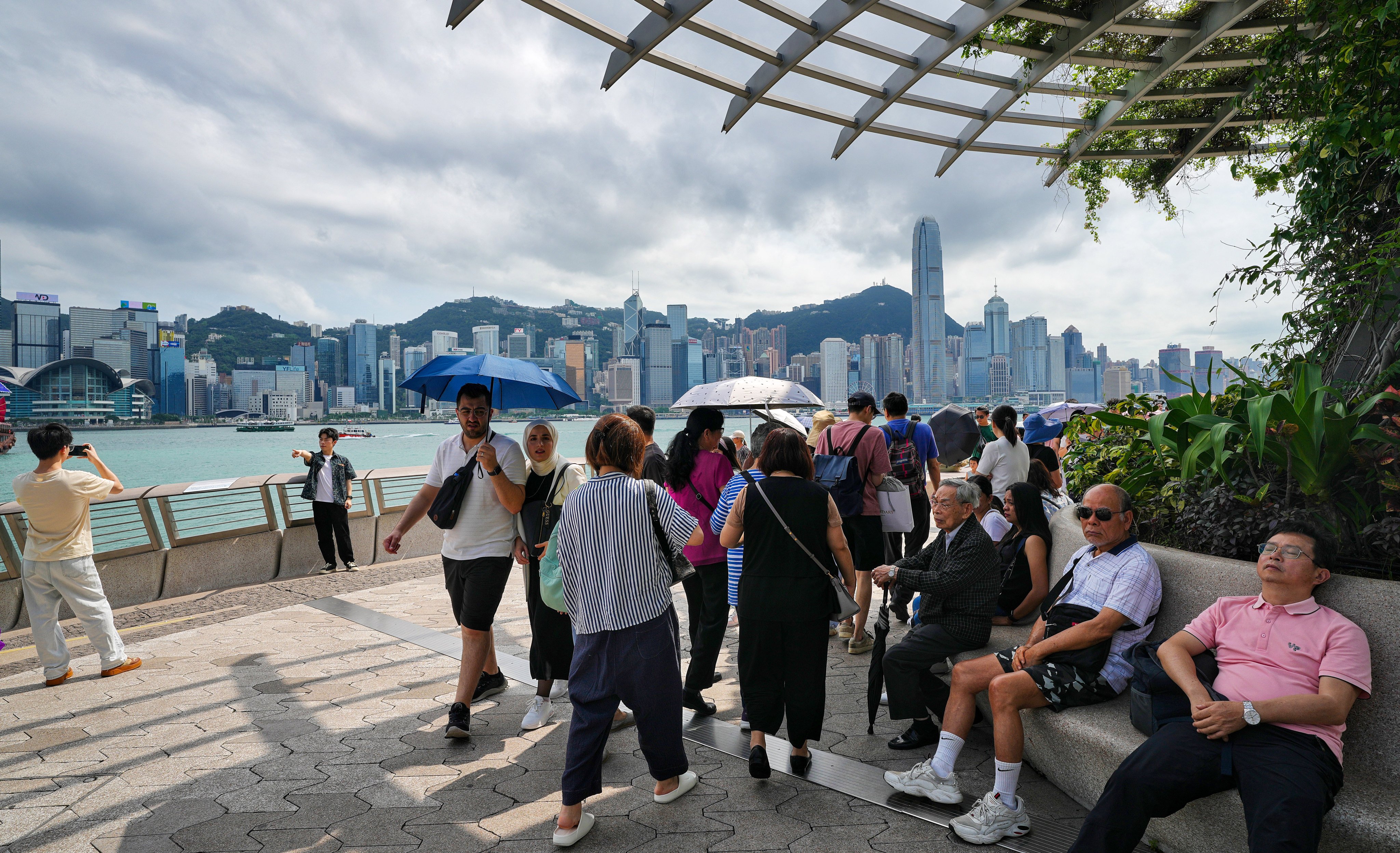 Tourists stroll along the Tsim Sha Tsui promenade and take photos of Victoria Harbour. Photo:  Elson Li