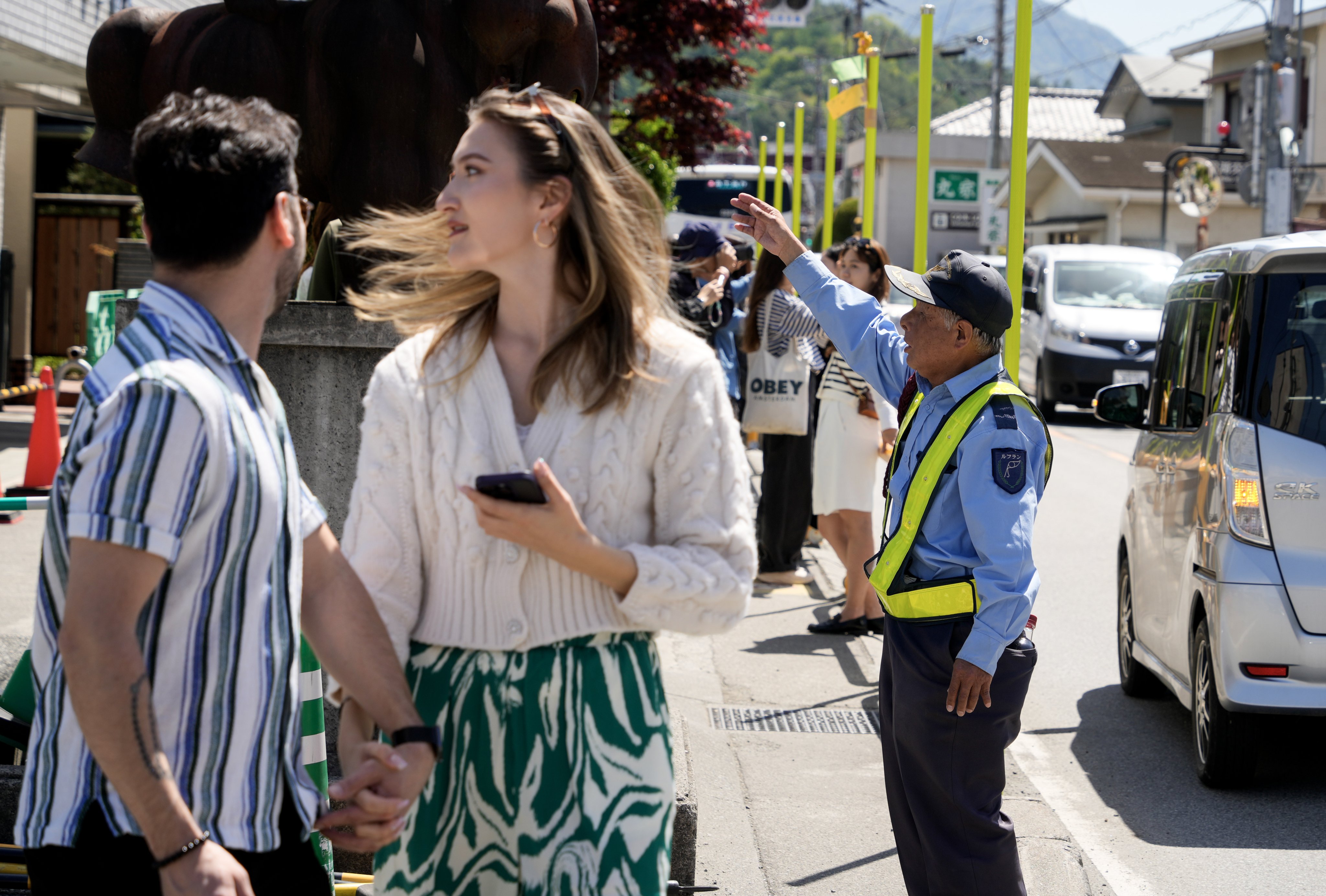 A security guard gestures towards foreigners as they gather on in Fujikawaguchiko, north of Japan’s Mount Fuji. Japan has been encouraging immigration to combat labour shortages. Photo: EPA-EFE