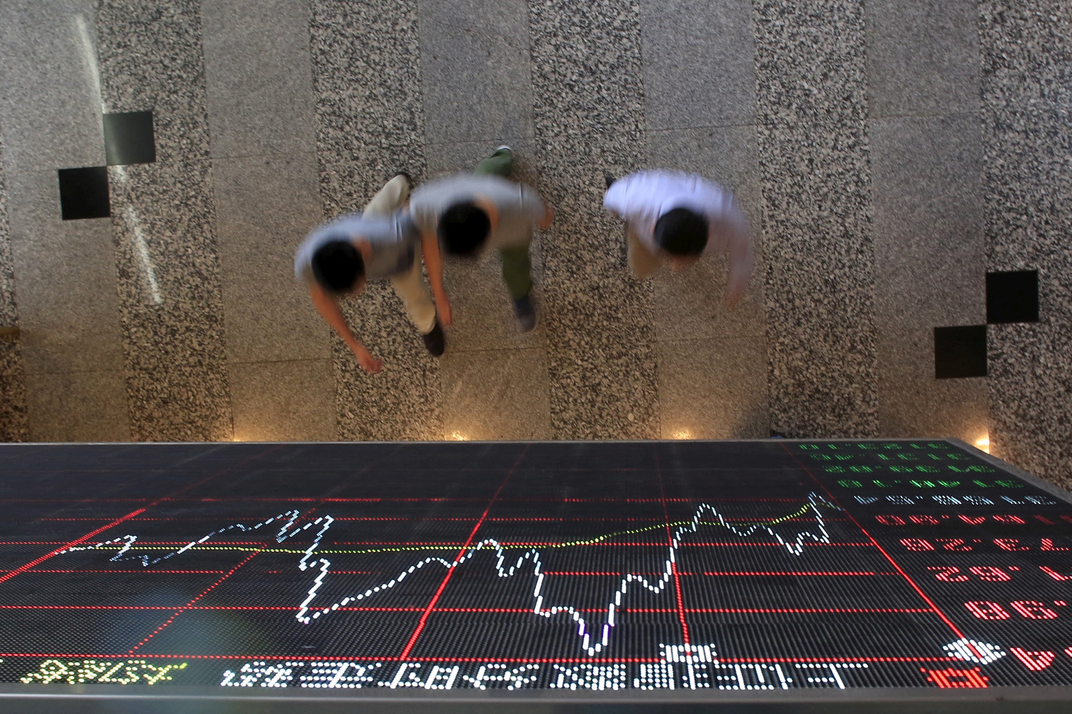 People walk under an electronic board showing stock information at the Shanghai Stock Exchange. Photo: Reuters