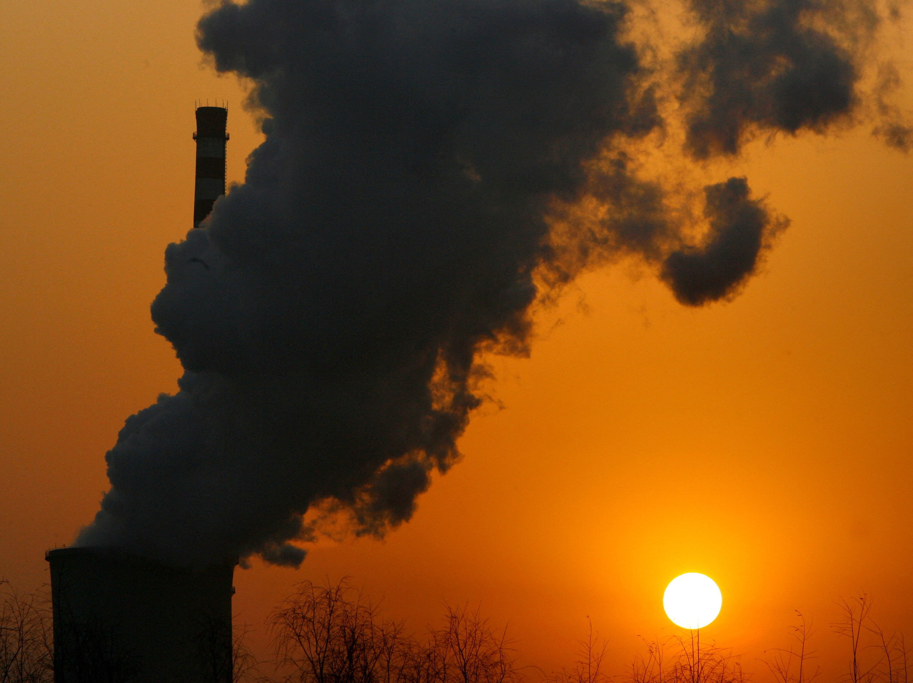 The sun sets next to a smokestack from a coal-burning power station in Beijing. Photo: Reuters