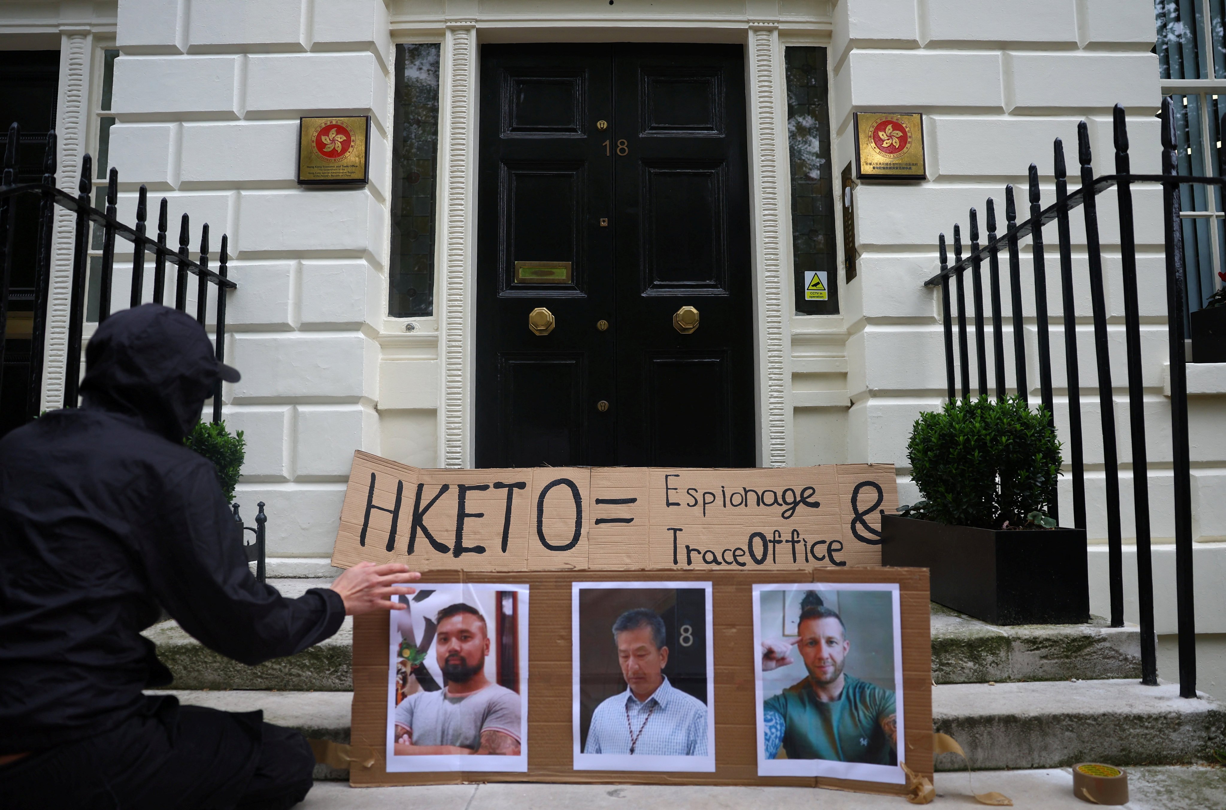 A protester places a placard showing three men charged with spying for Hong Kong outside the city’s Economic and Trade Office in London. Photo: Reuters