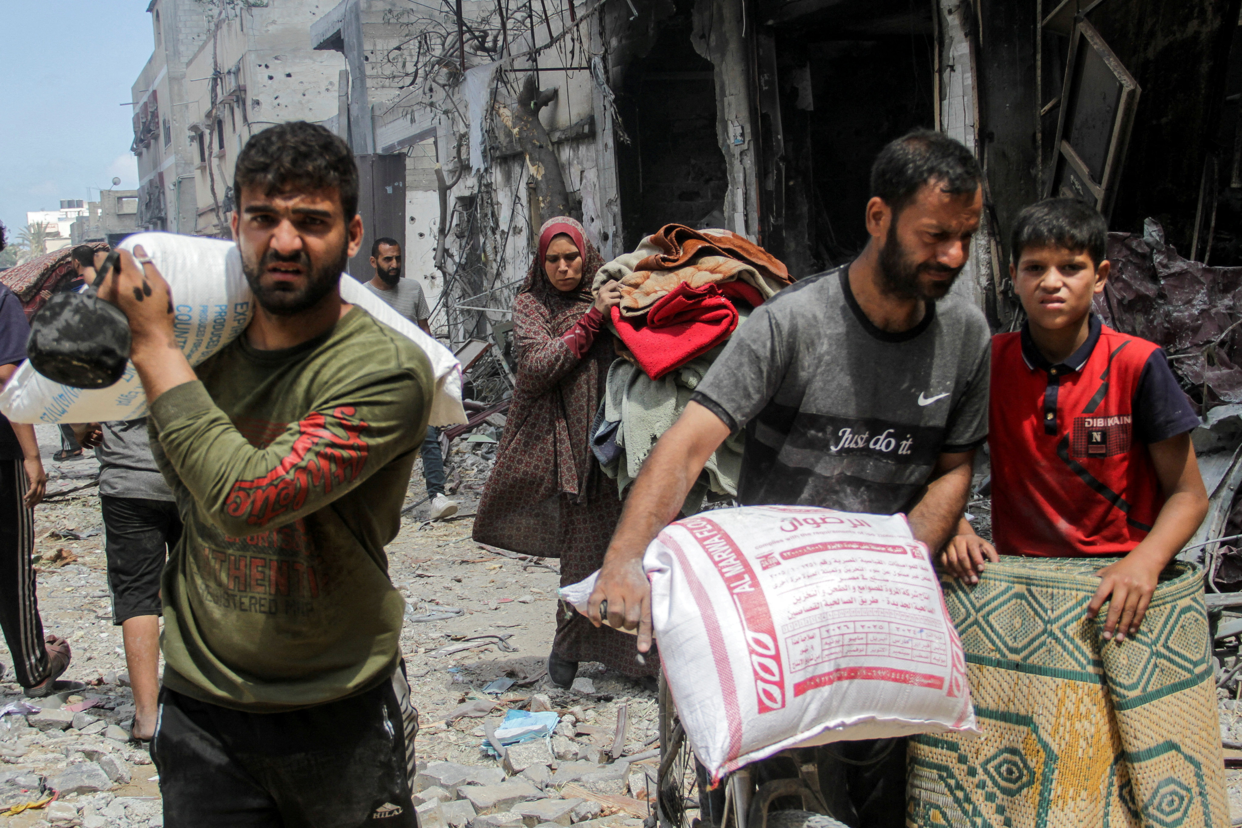 Palestinians in Gaza City carrying belongings and bags of flour. Photo: Reuters